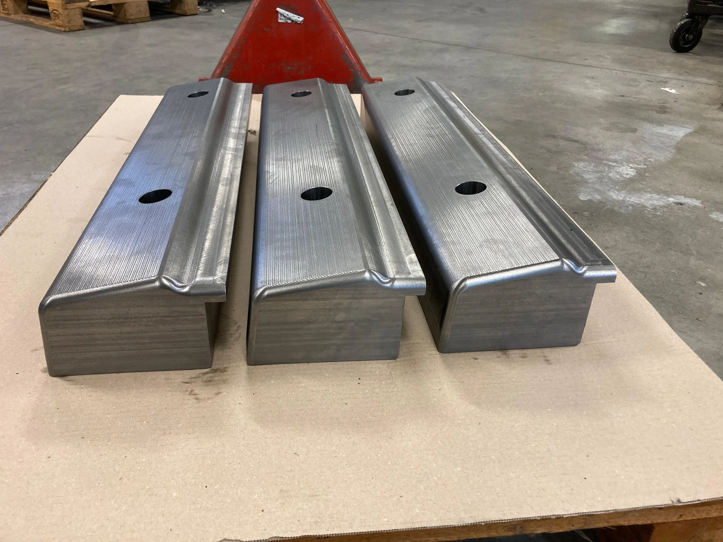 Tre blocchi di metallo lucido su un banco di lavoro in un ambiente industriale.