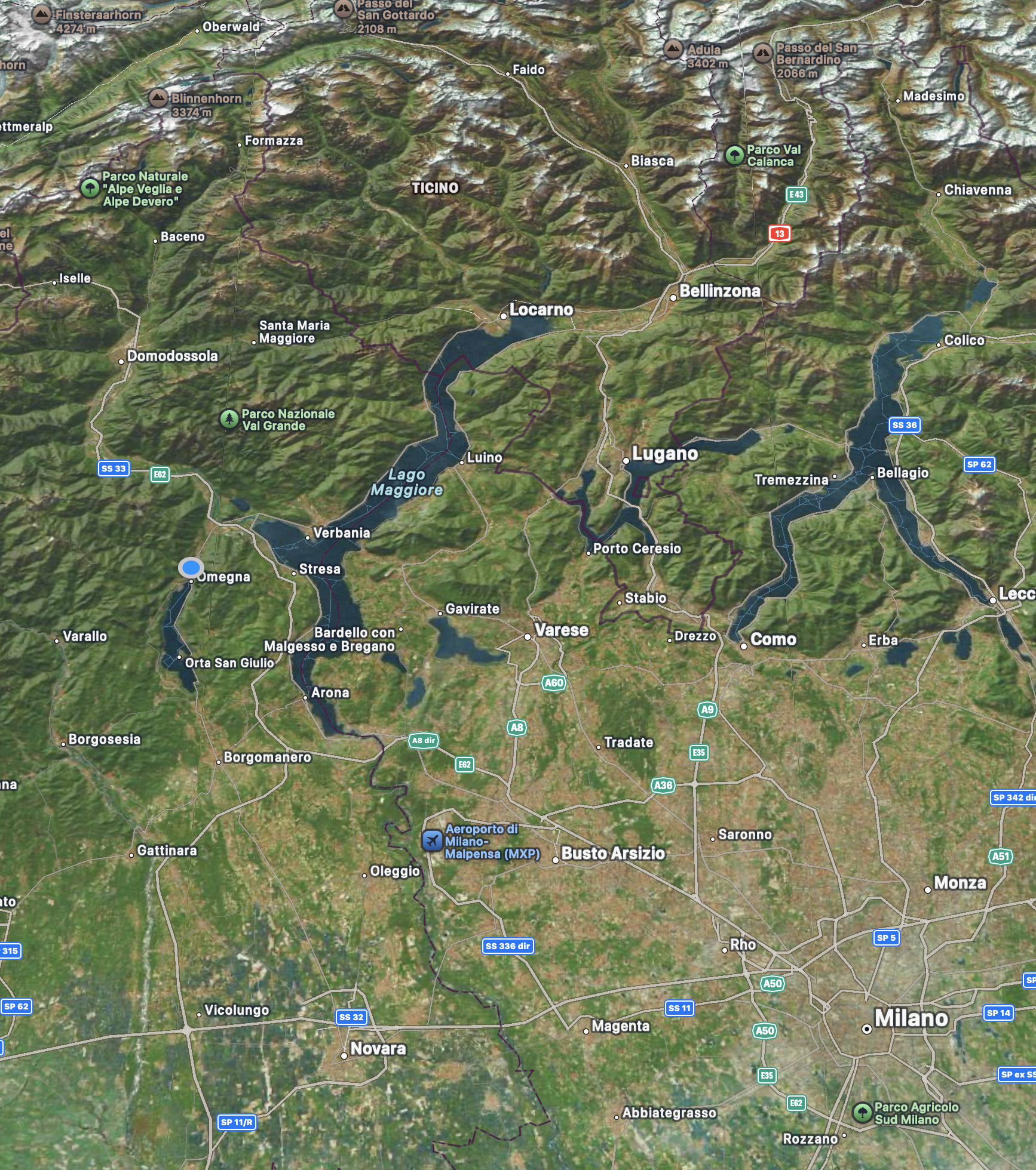 Carta geografica dell'area tra Milano e il Lago Maggiore, con città come Varese, Como, Saronno e l'aeroporto di Malpensa, visualizzando anche strade principali e parchi naturali.