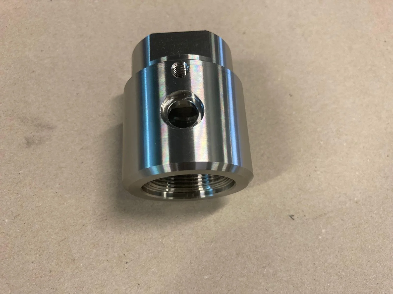 Componente meccanico cilindrico in metallo con fori e filettature