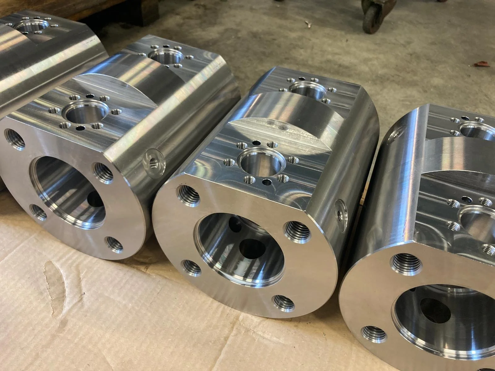 Parti meccaniche in metallo lucido, cilindri con fori e filettature.