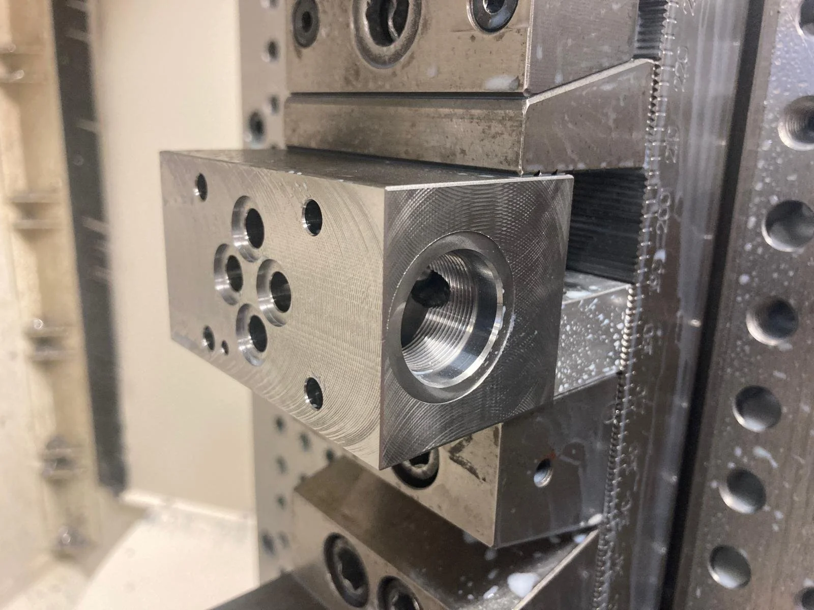 Particolare di un blocco di metallo con fori e filettature, parte di uno stampo o attrezzatura industriale.