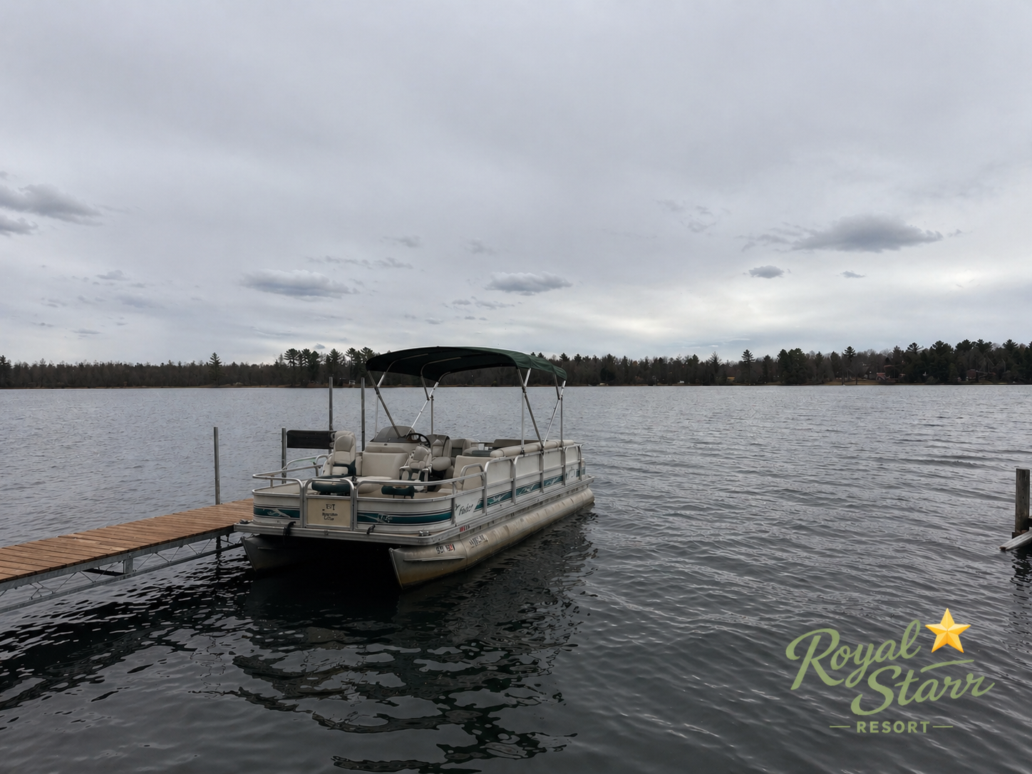 A pontoon boat docked at a wooden pier on a lake under an overcast sky, with trees lining the distant shoreline and a "Royal Star Resort" logo in the lower right corner.