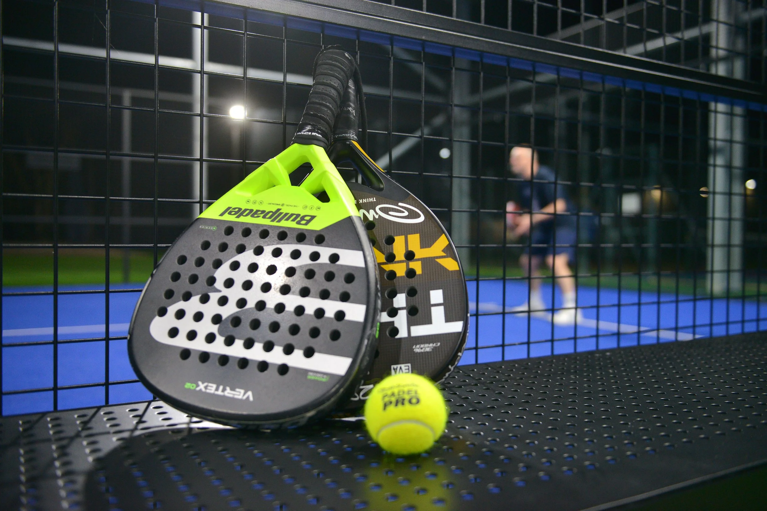 A man playing tennis on a blue hard court, preparing to hit a ball with a racket.