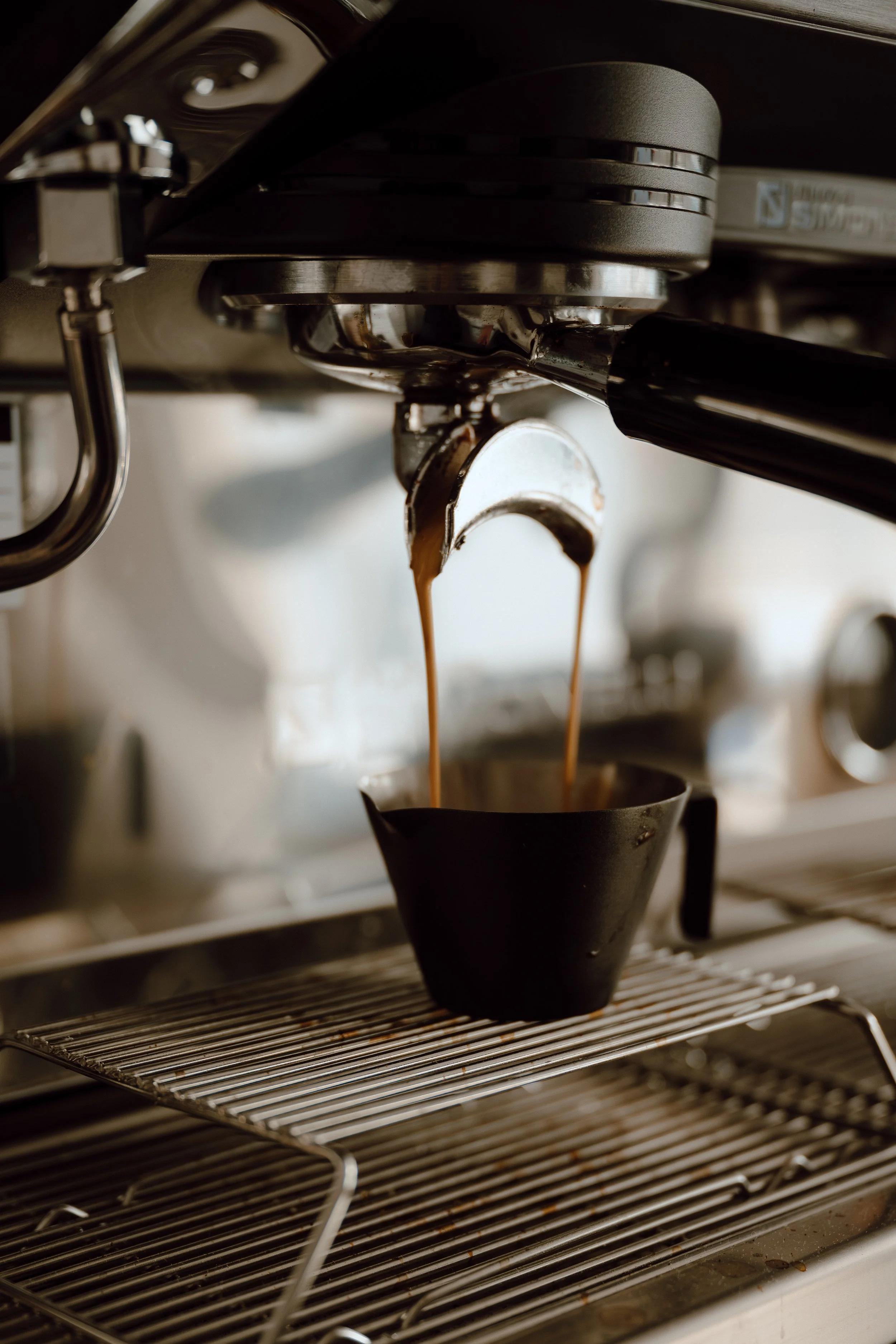 Close-up of an espresso machine brewing coffee into a small black cup.