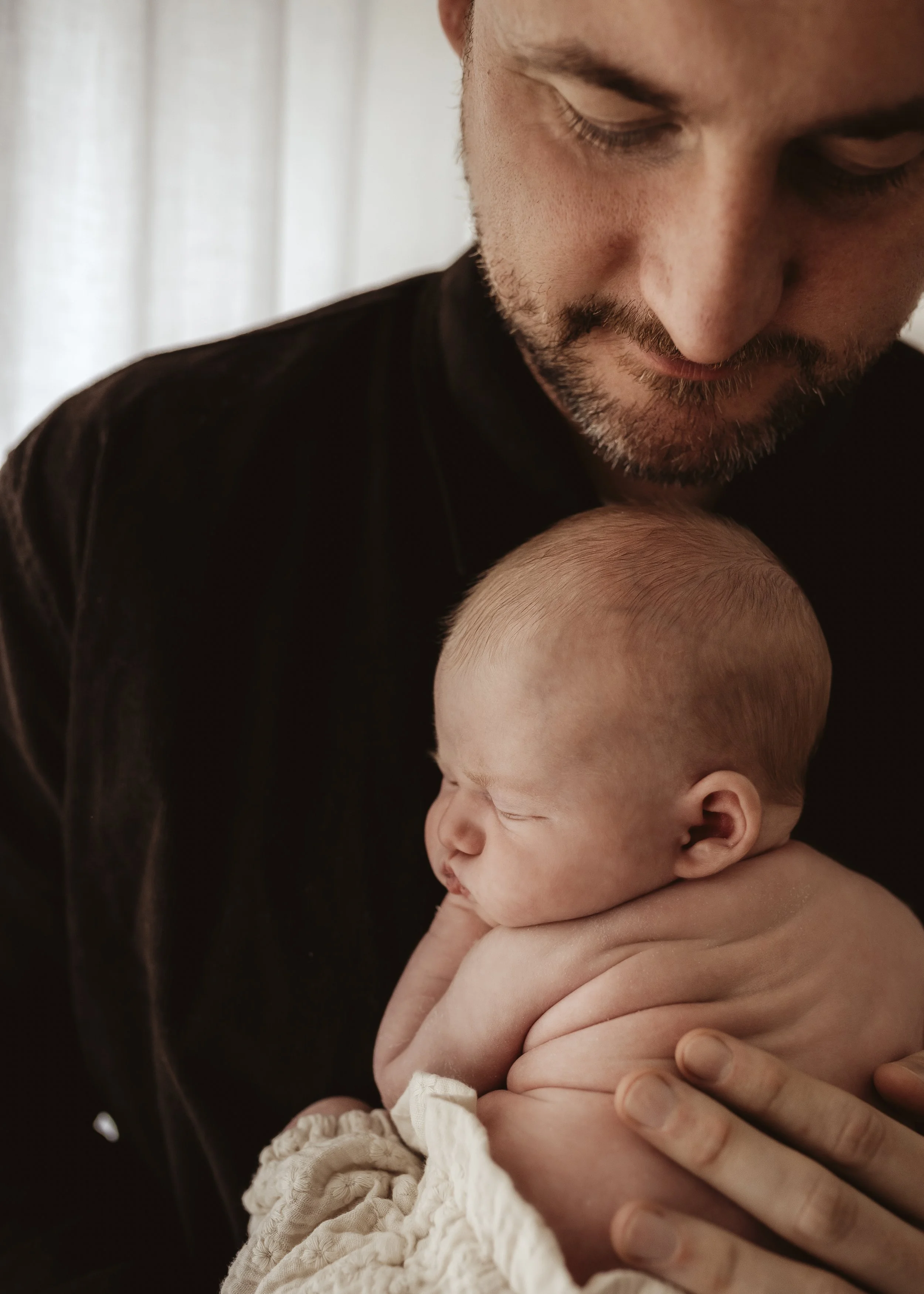 Close-up of a man holding a sleeping baby in his arms.