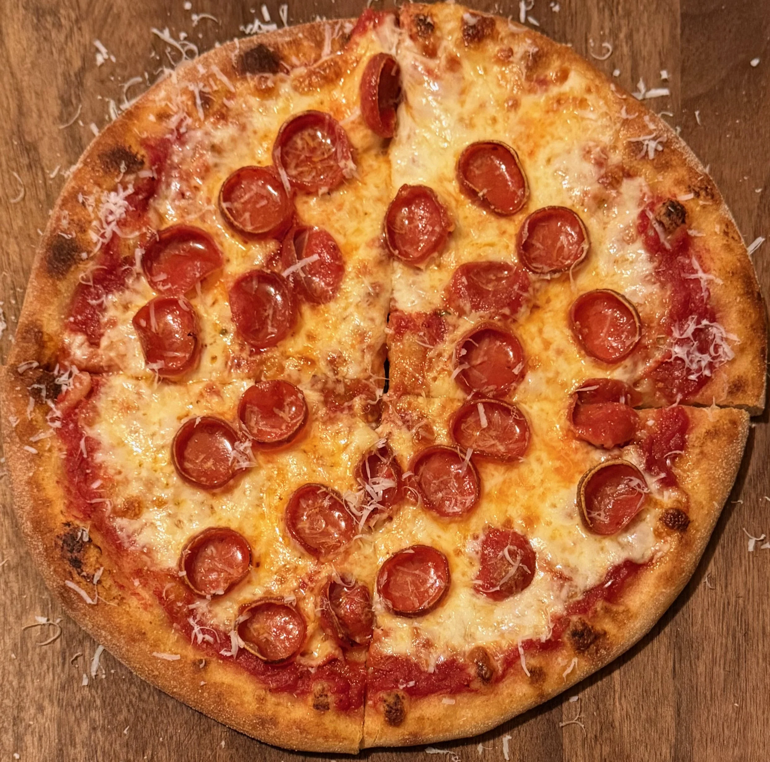 Handcrafted 10-inch NY-style pizza from Grickey’s Pizza in Seattle, with golden-baked crust, melted mozzarella, fresh tomato sauce, and evenly spaced pepperoni, ready to serve at farmers markets, private events, and catered gatherings.