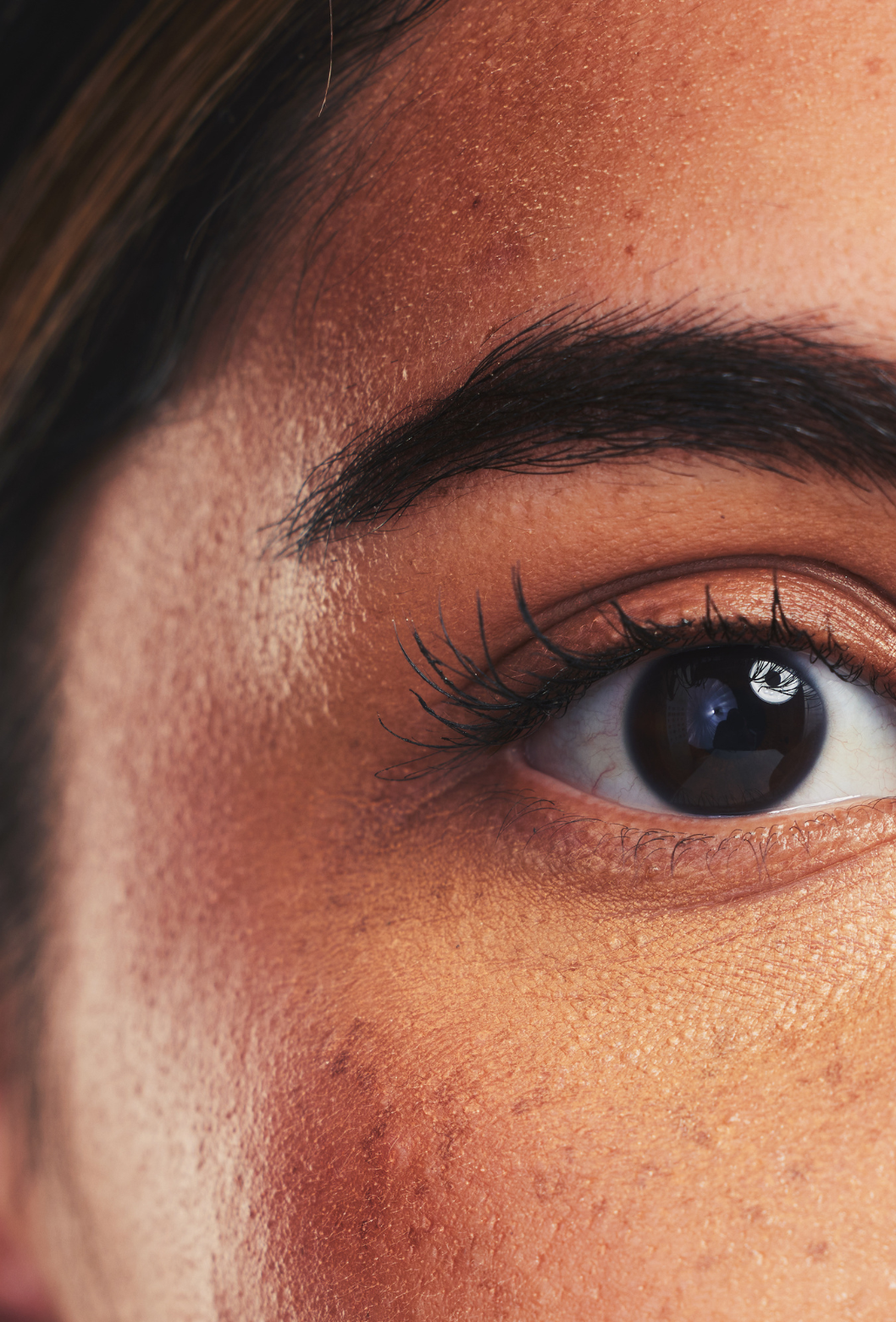 Close-up de um olho humano com destaque para sobrancelha, cílios e pele ao redor.