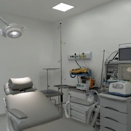Sala de cirurgia com cama hospitalar, dispositivos médicos, equipamentos de monitoramento e iluminação cirúrgica