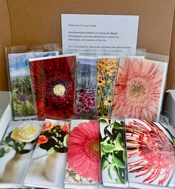 Collection of printed photos of various flowers arranged on a surface with a message or letter in the background.