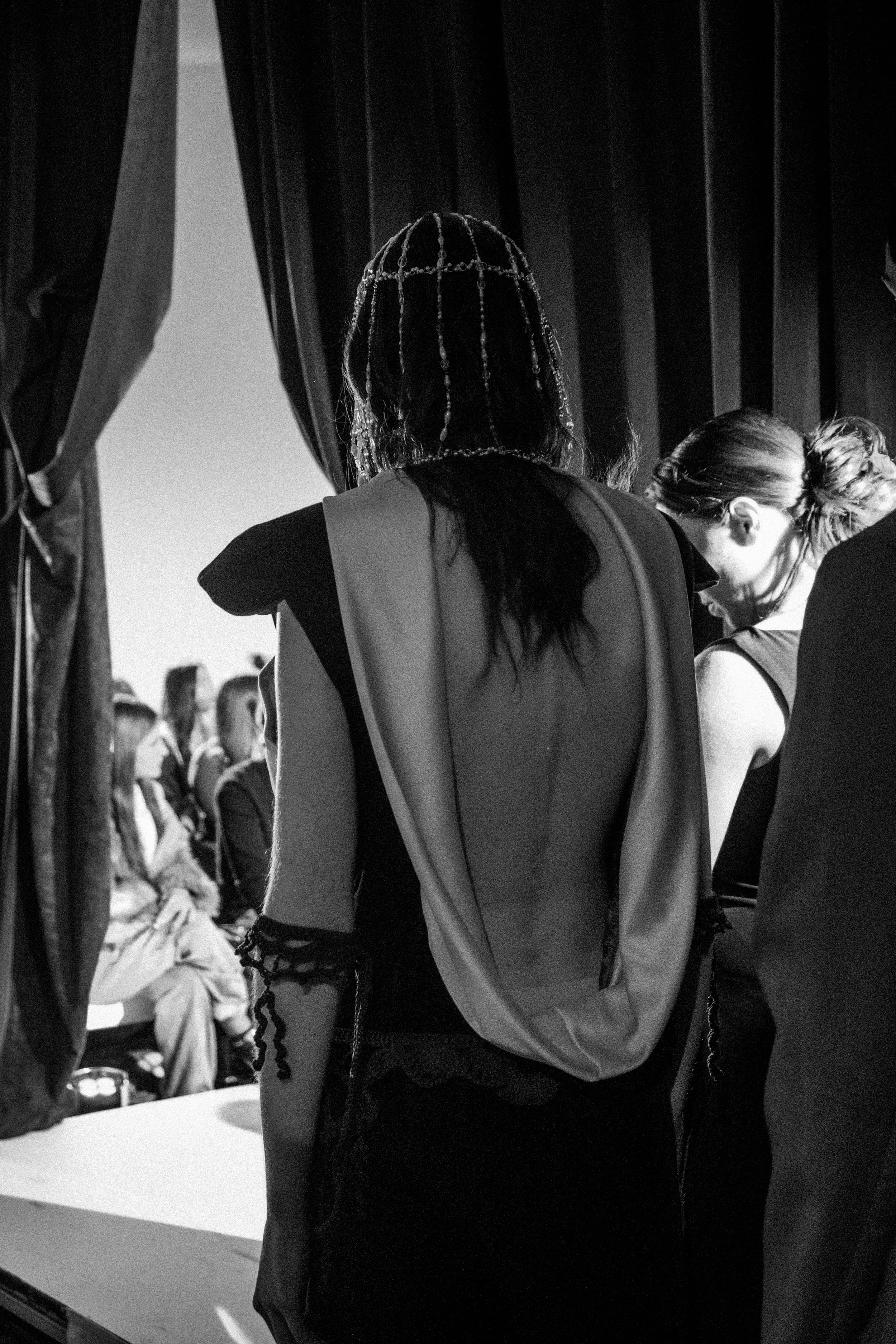 Backstage at a fashion show with models and attendees, black and white