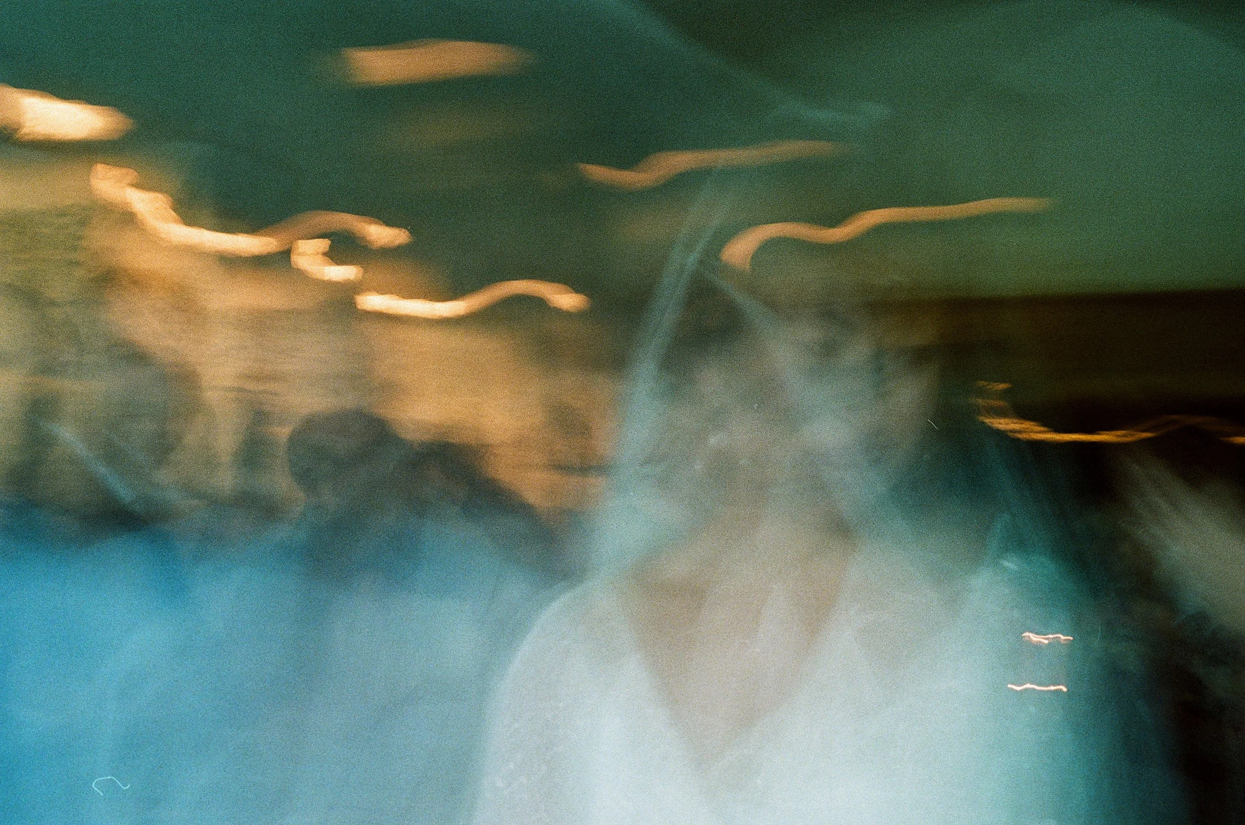 An abstract, blurred photo with streaks of light and indistinct figures, giving a dreamy or nighttime atmosphere.