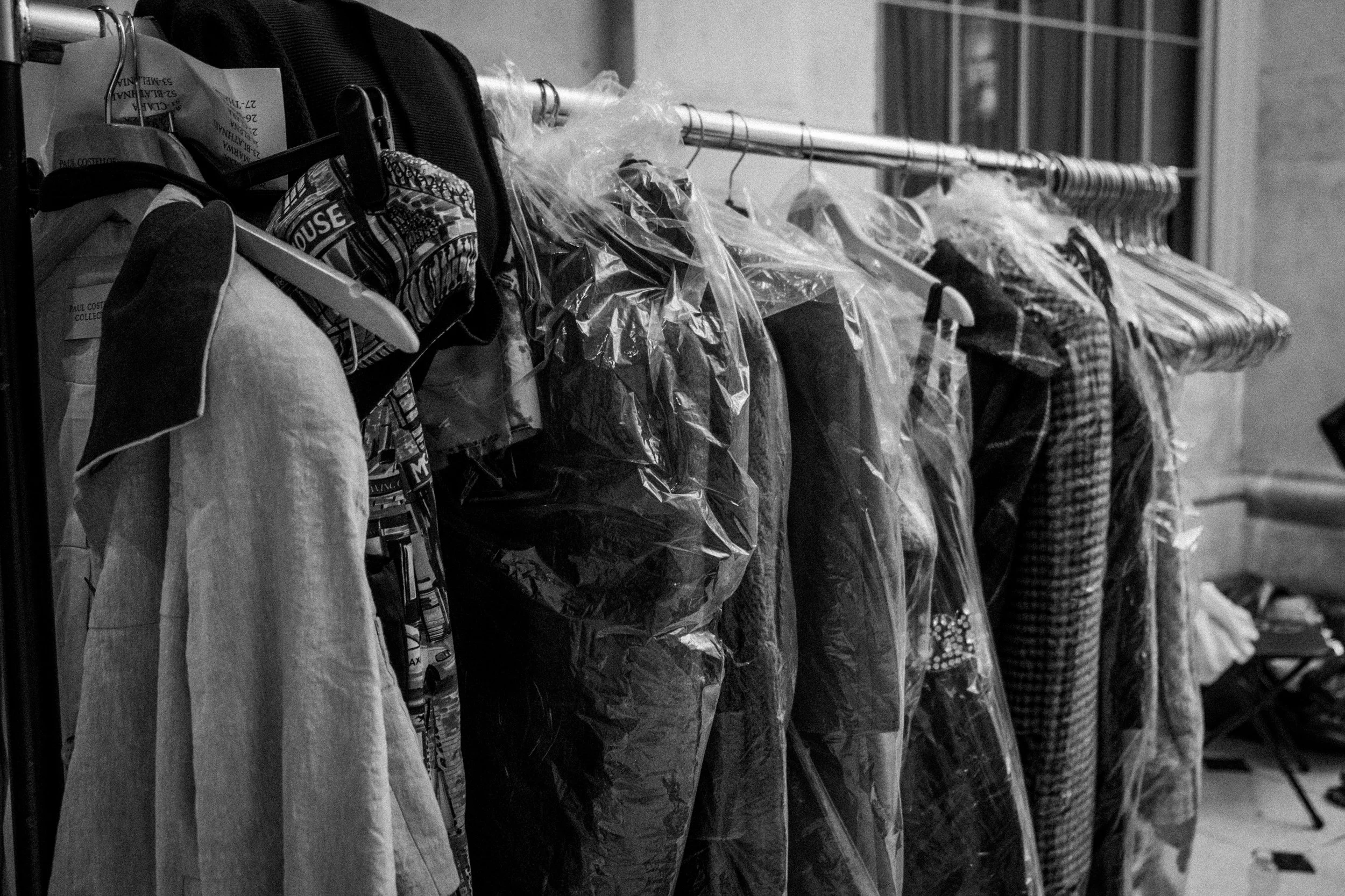 Clothes on hangers and in plastic covers hanging on a clothing rack in black and white