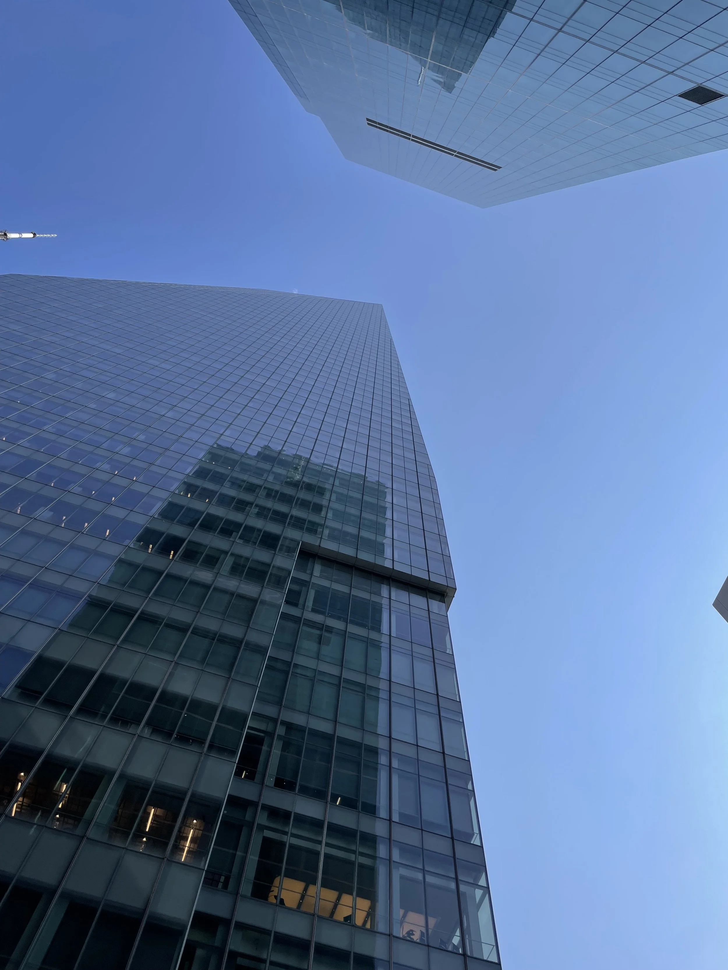 Looking up at tall glass skyscrapers against a clear blue sky.
