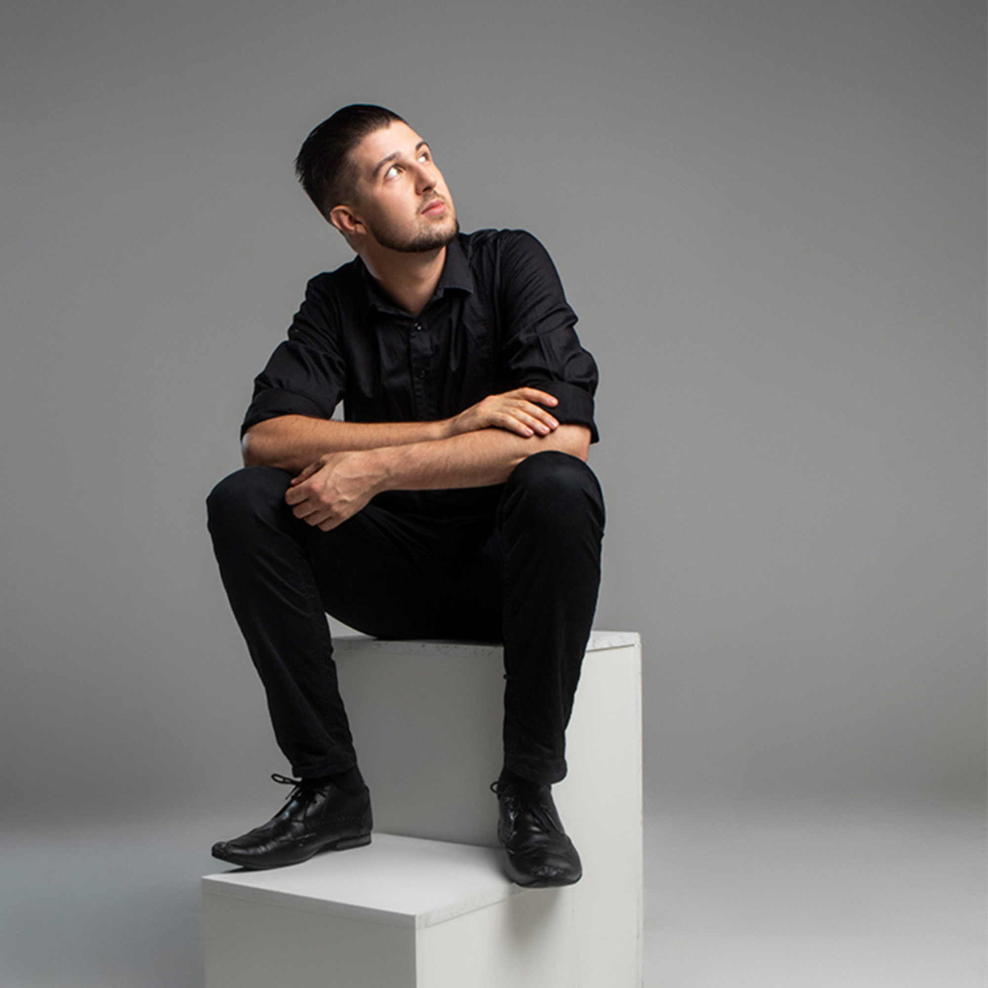 Kai Mann-Robertson in all black sitting on white stairs