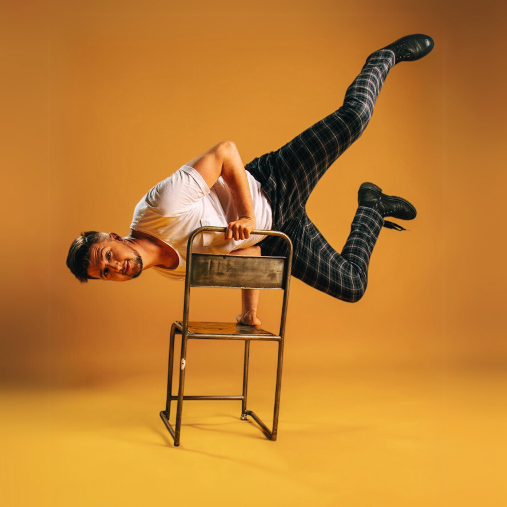 Kai Mann-Robertson Suspended above a chair in a yellow studio