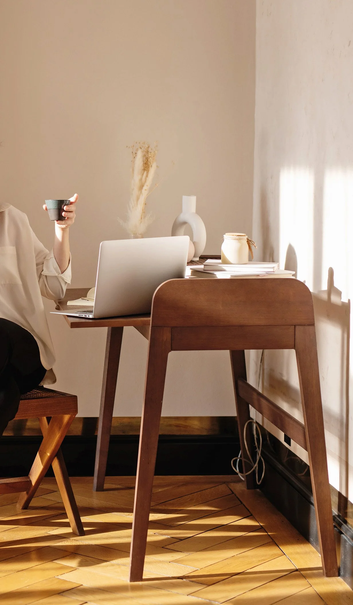 a woman who is sitting at her desk with her laptop and other desk accessories on it while she's holding a cup in her hand