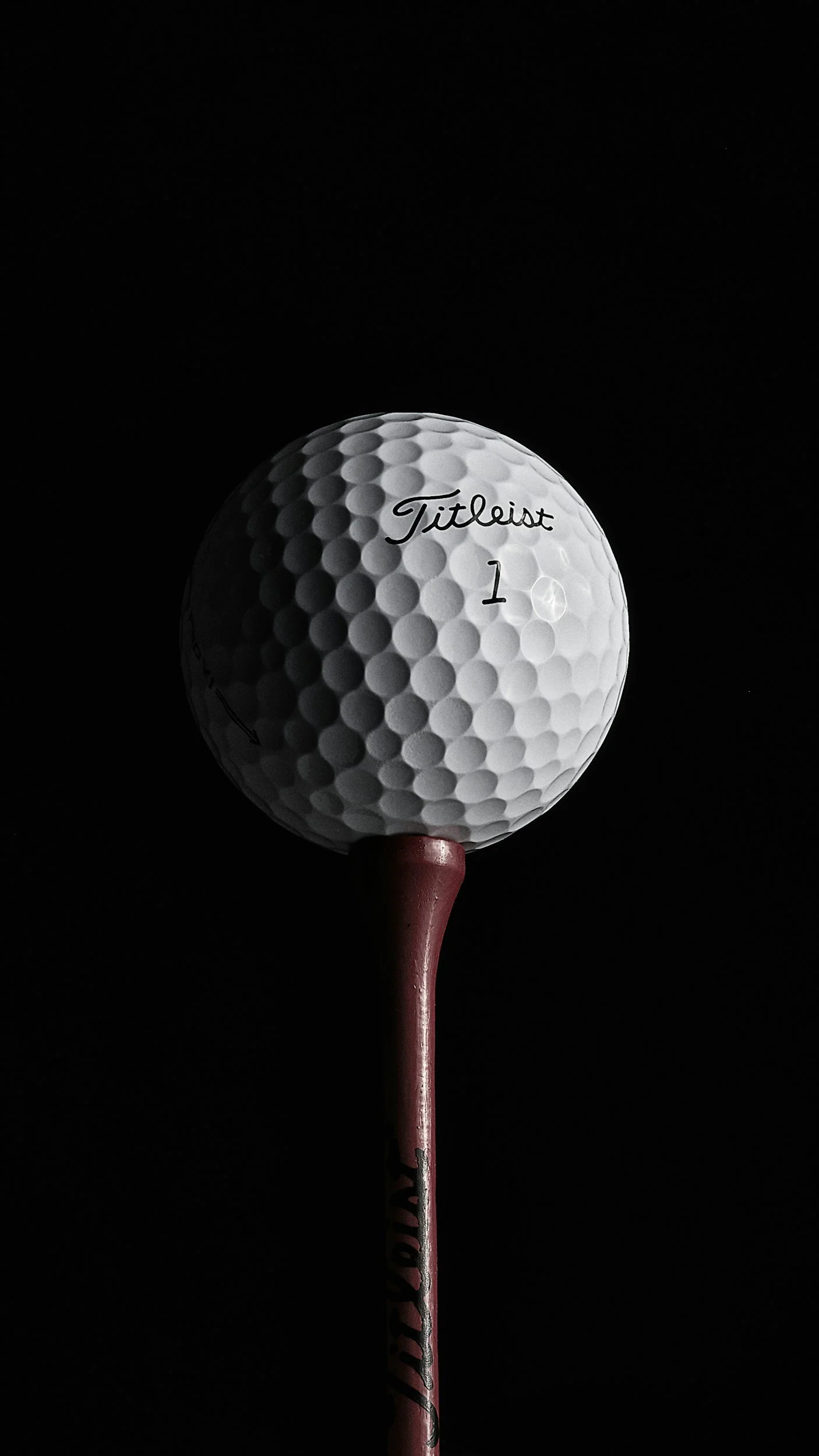 A golf ball on a tee against a black background
