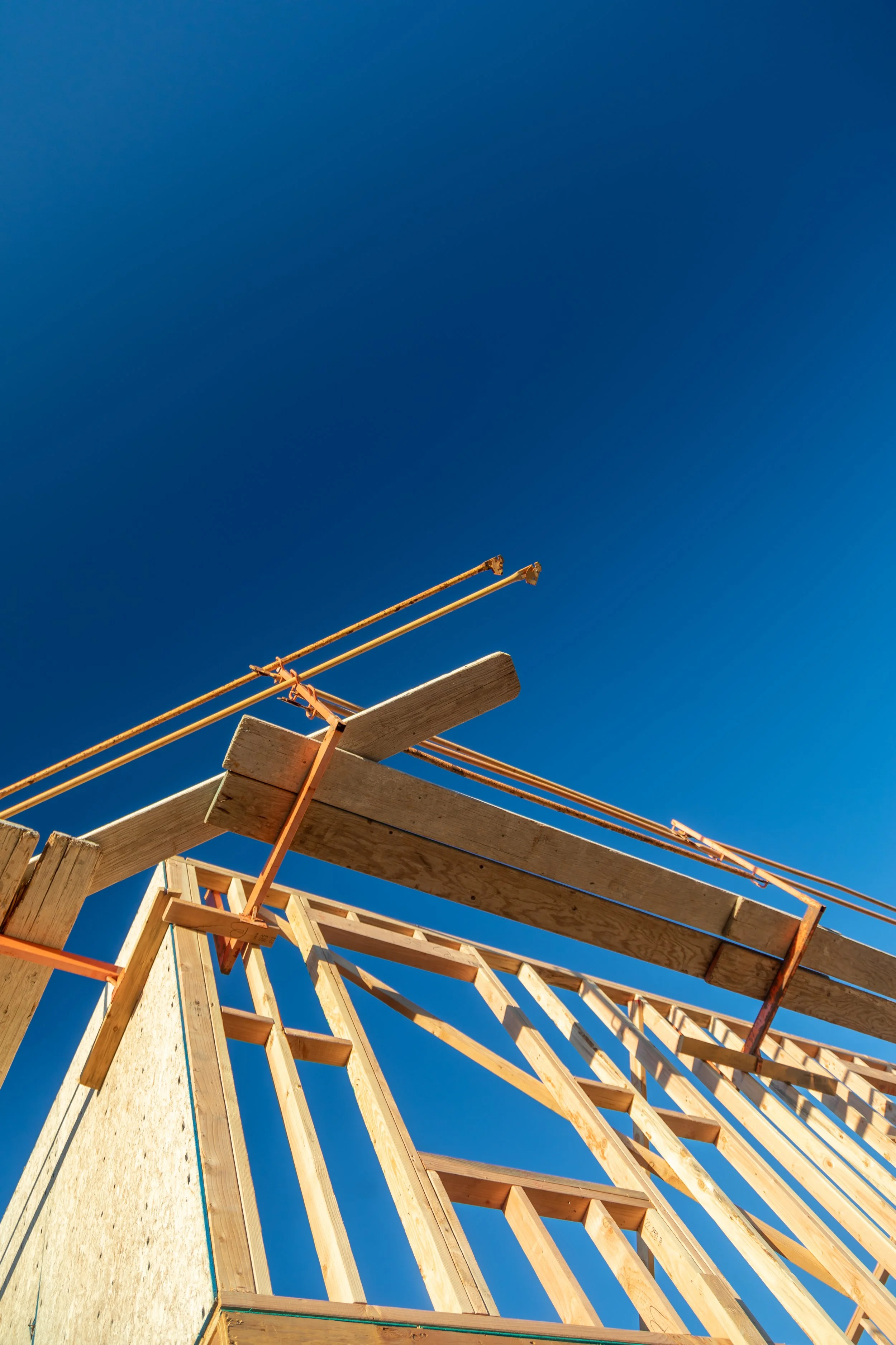 Construction site with wooden framework and blue sky in the background.
