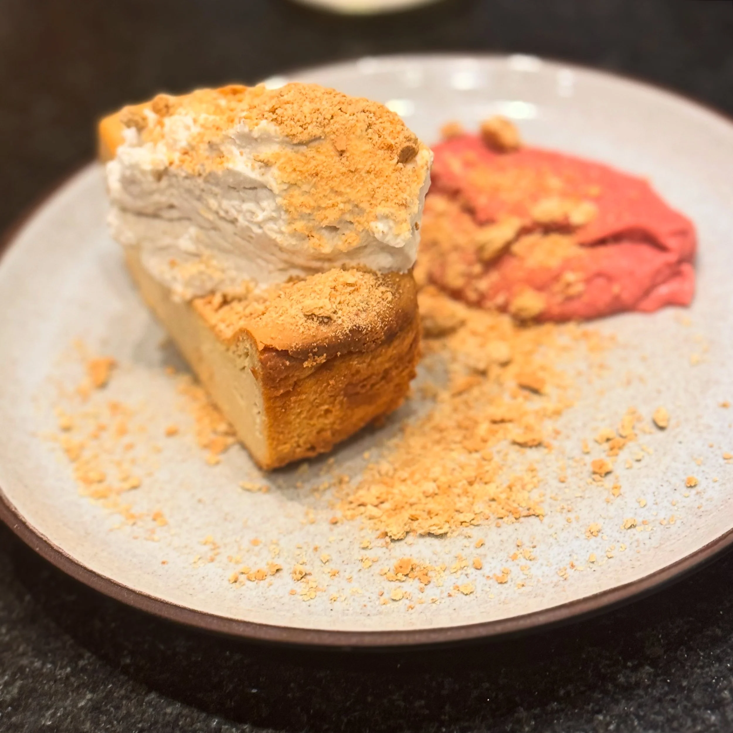 A slice of pie with a scoop of ice cream on top, served on a white plate with pink pie filling and crumbs around the plate.