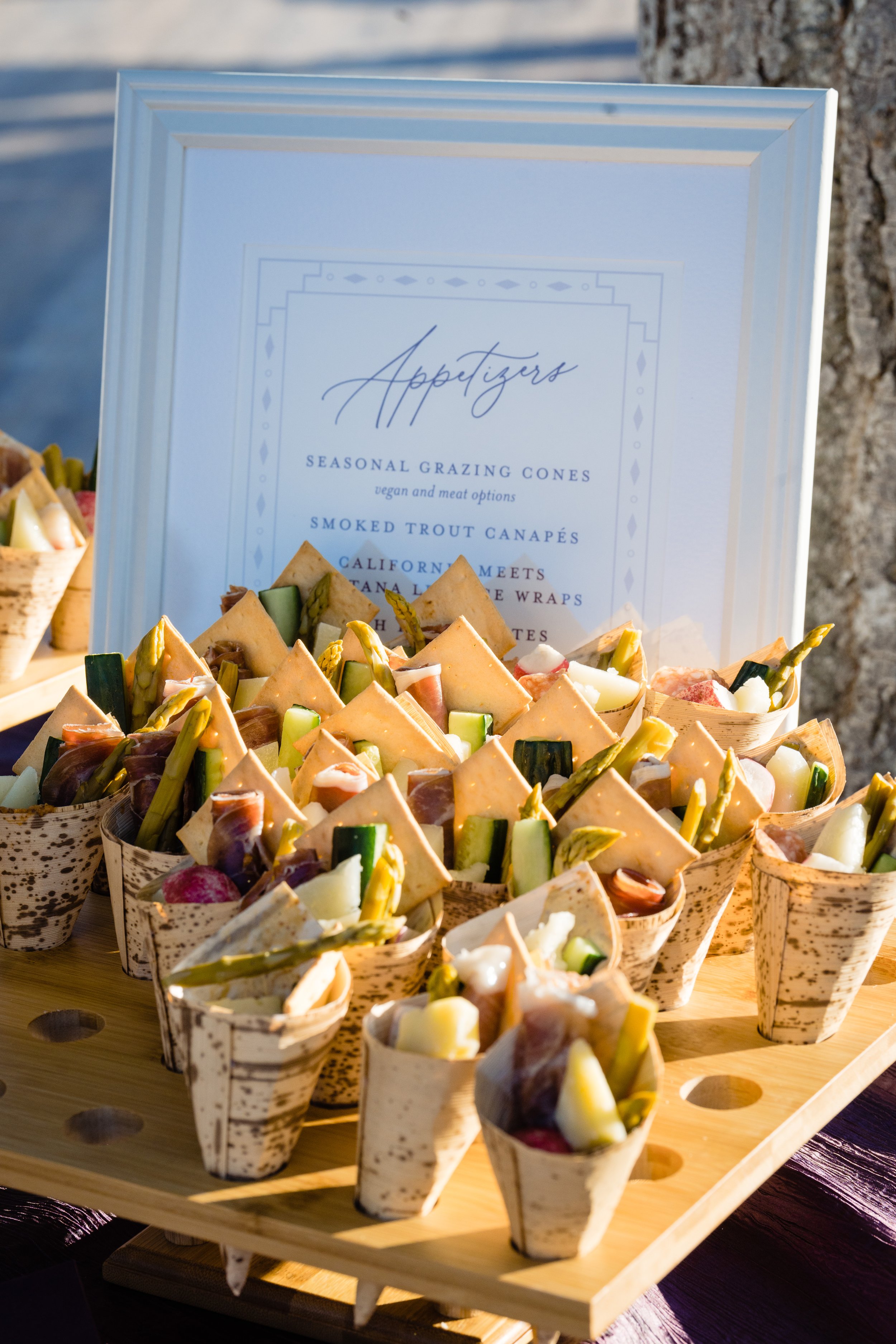 Tray of assorted appetizers in cone-shaped containers with a menu sign in the background