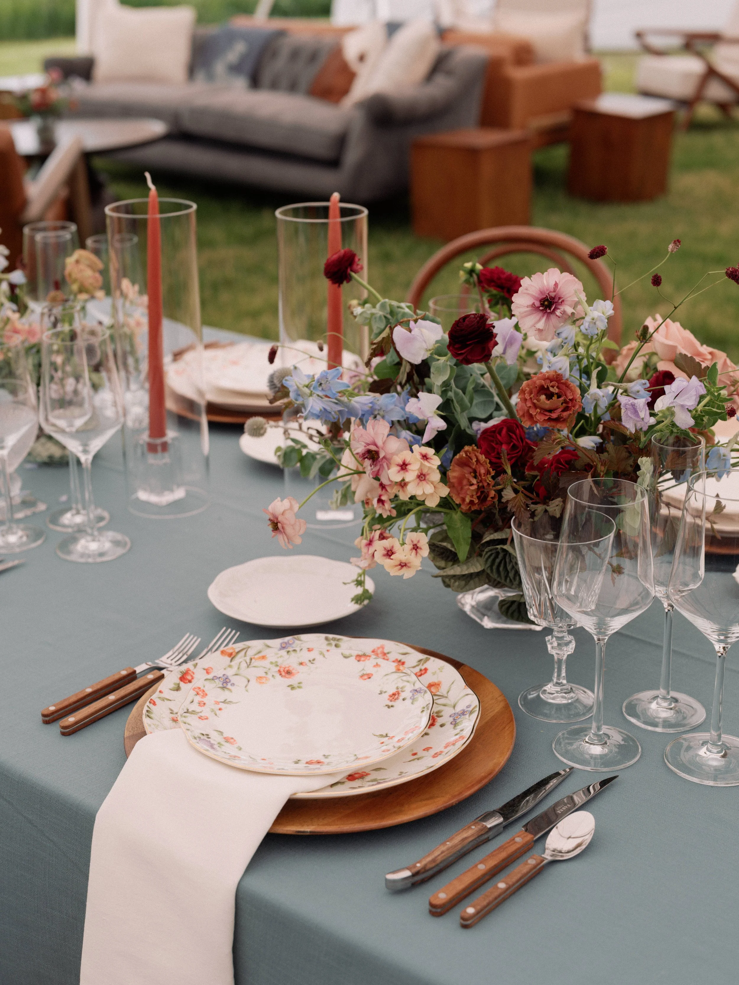 Styled wedding reception tablescape with blush and terracotta plates, copper cutlery, floral centerpiece, and glassware, designed by Wild Blume