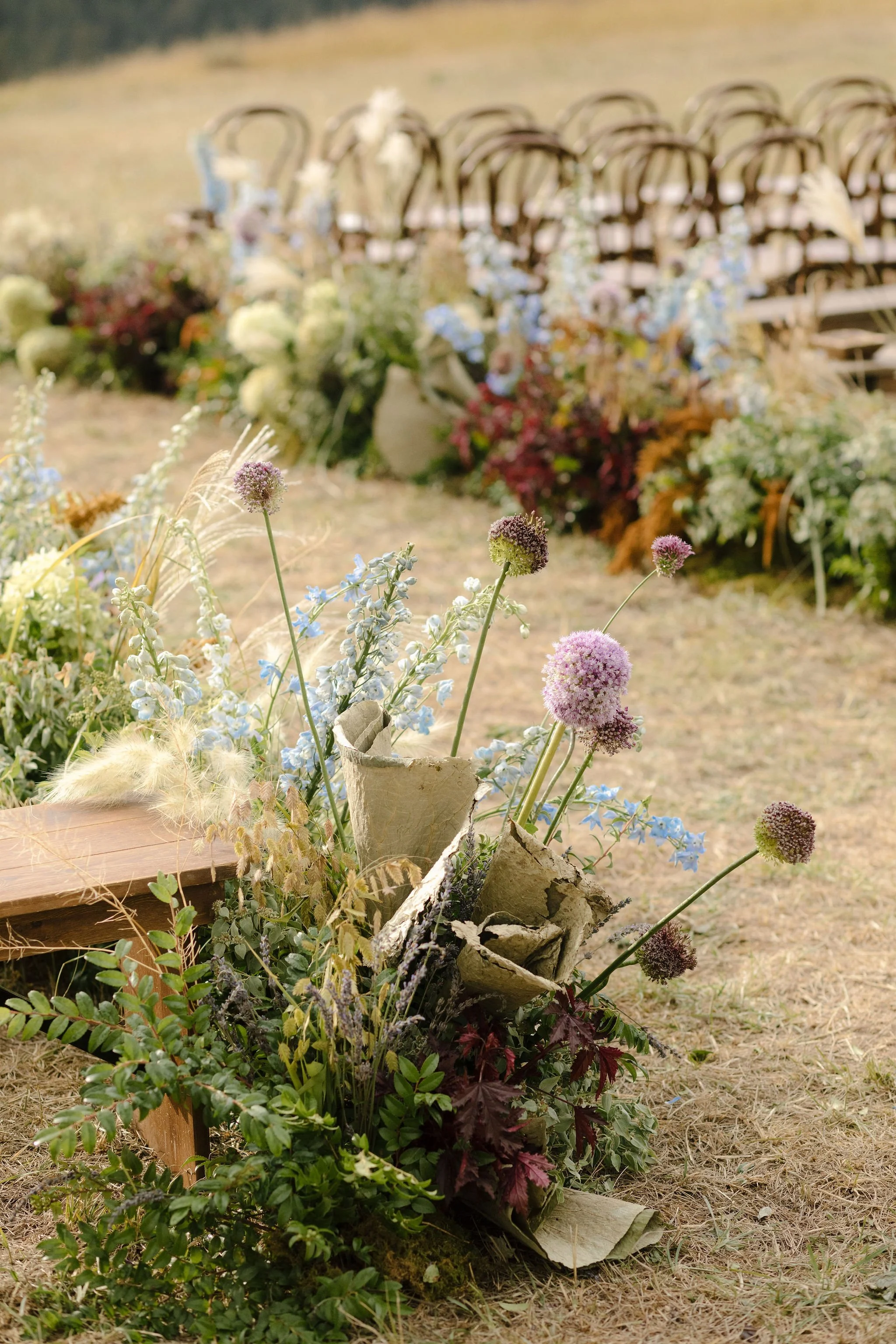 Decorative floral arrangement with various flowers and greenery in a rustic outdoor setting.