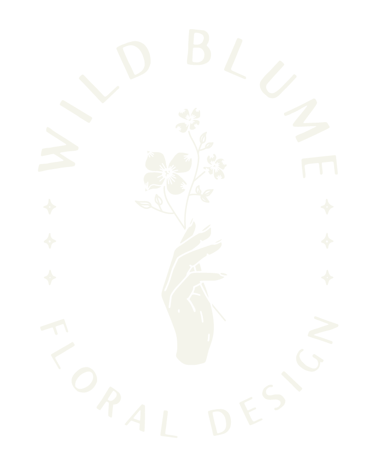 A black background logo with a white hand holding a flower. The text "WILD BLUE" is arched above the hand, and "FLORAL DESIGN" is written below, with decorative stars on each side.