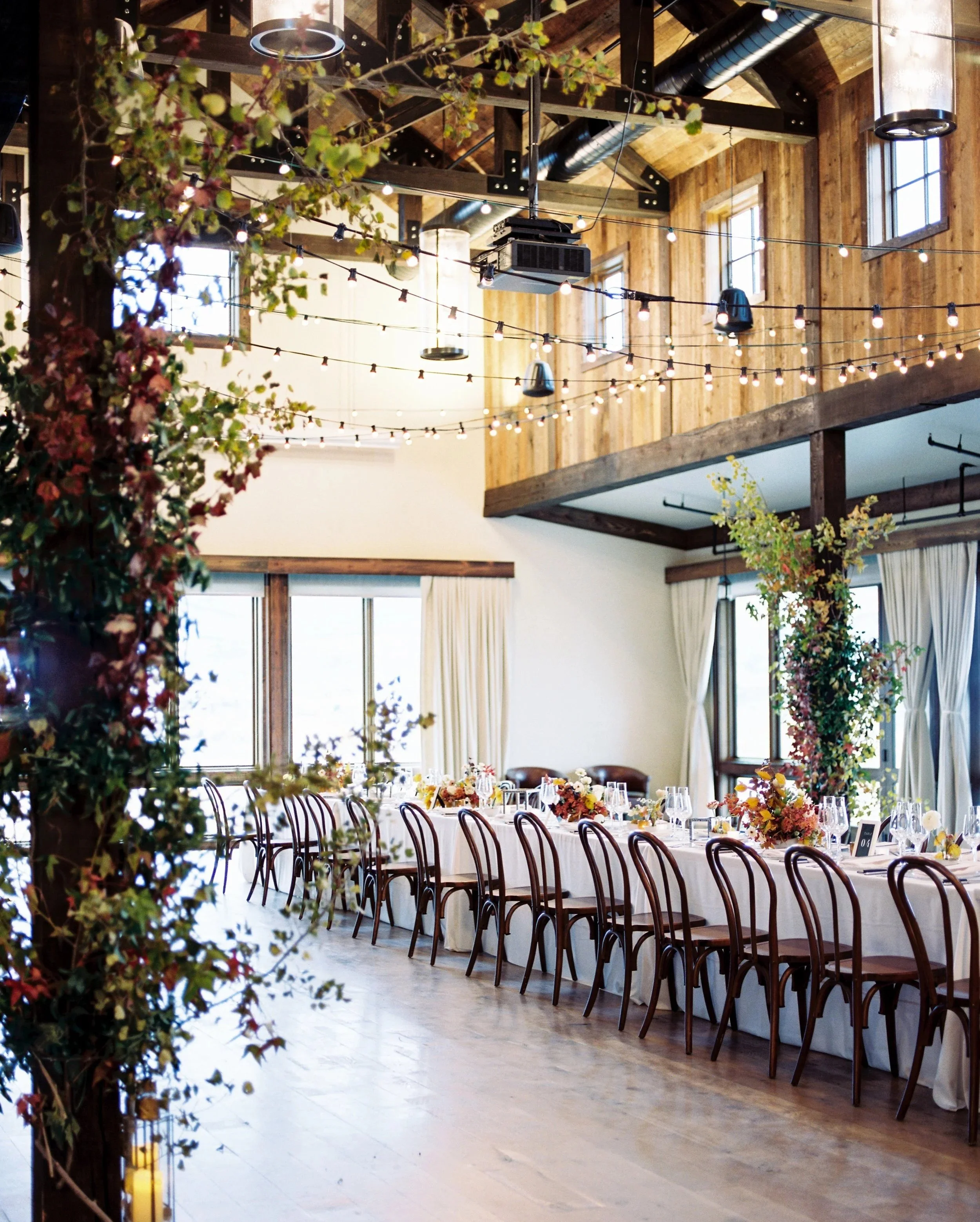 Lush floral installation cascading along a long reception hall with extended dining tables, designed by Wild Blume