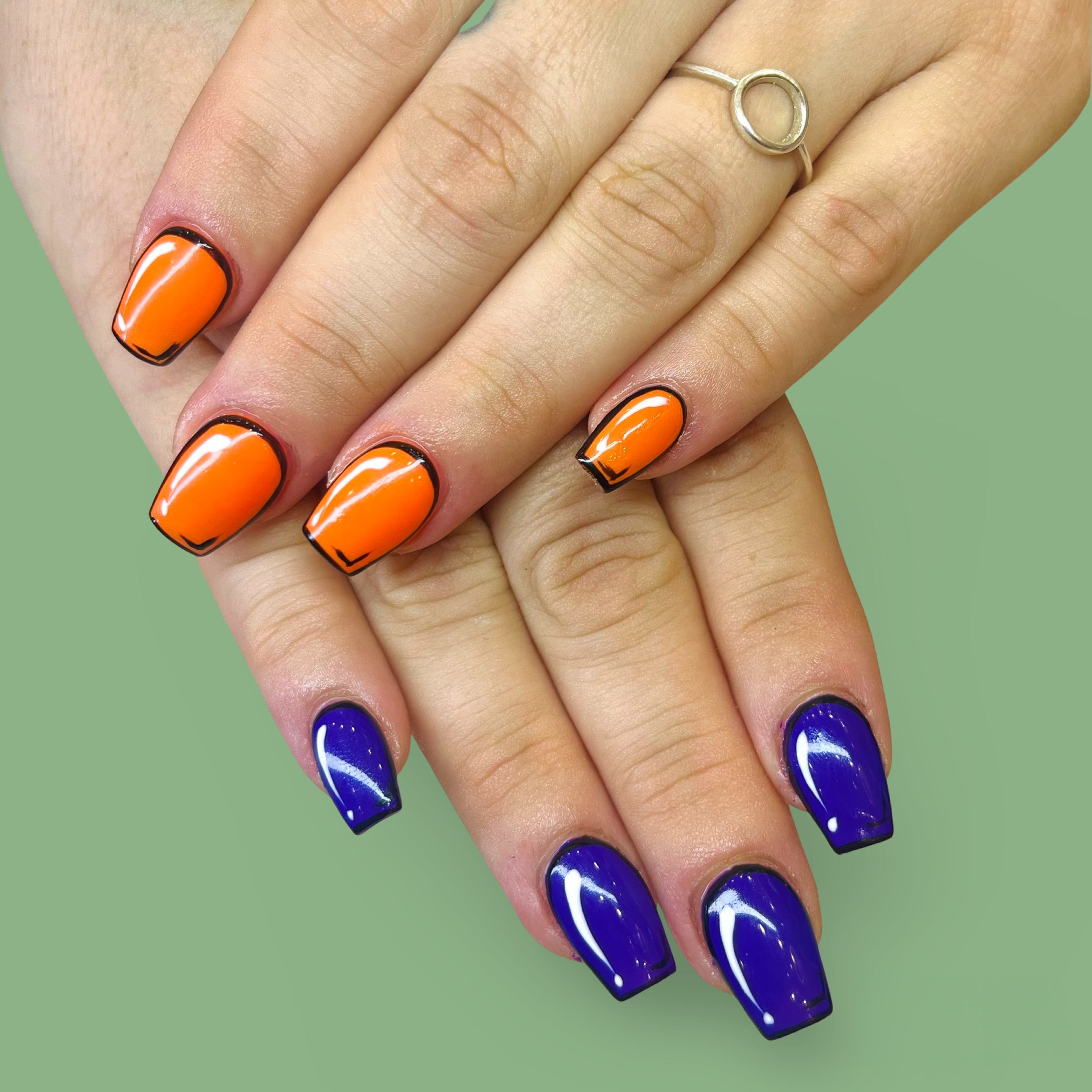 Hands with colorful, glossy, manicured nails; orange with black tips on the top hand and blue with black tips on the bottom hand, wearing a silver ring with a small circle on the top finger.