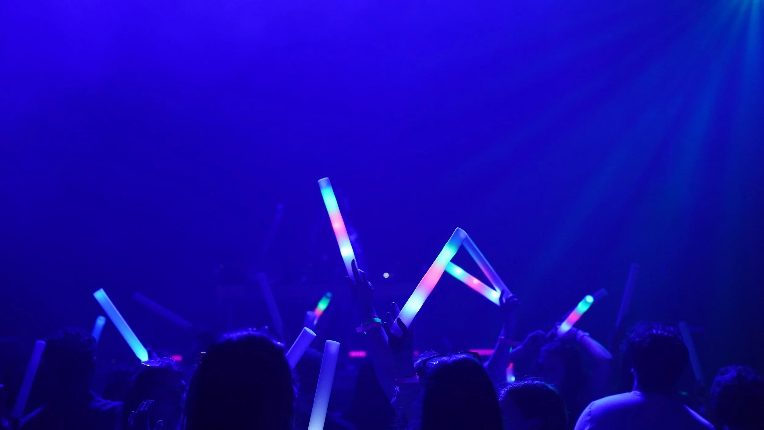 People at a concert or event holding colorful, glowing sticks in the dark. HSP event production in Boston MA