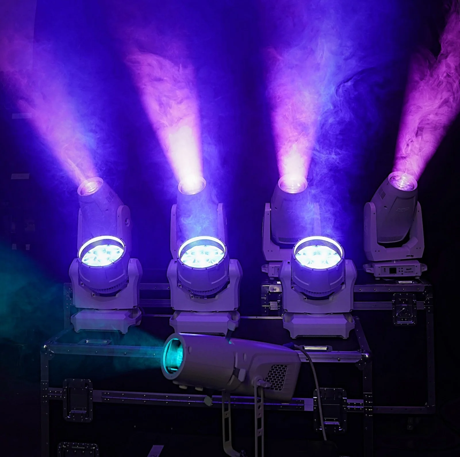 Four stage lighting fixtures emitting purple and blue light with visible smoke or haze. HSP event production in Boston MA