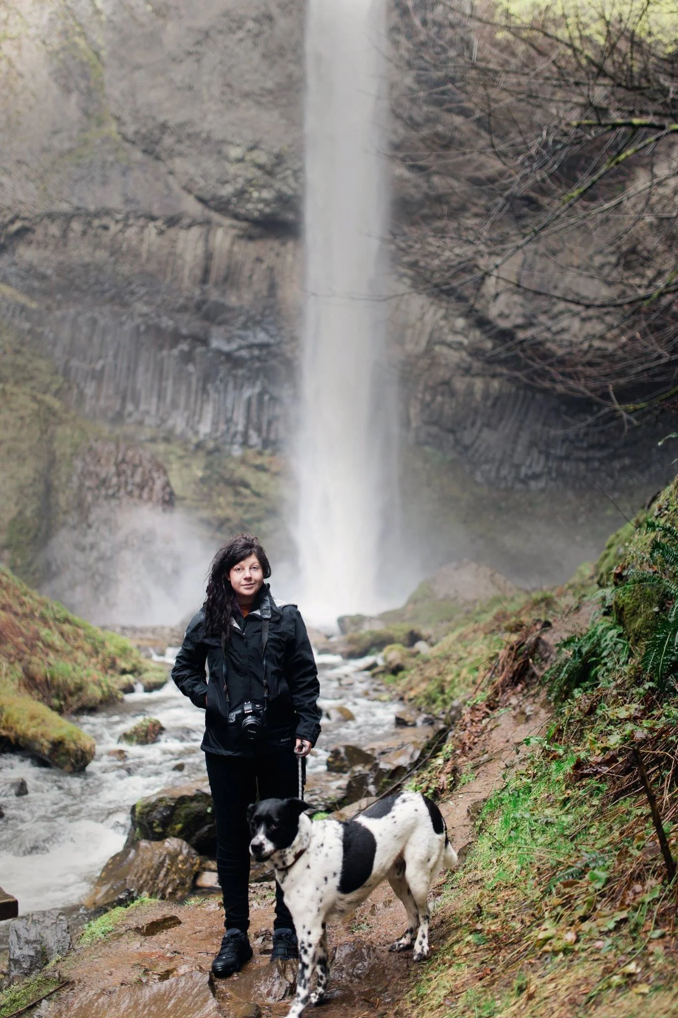 Photographer Leah Flores standing in front of a waterfall in the Pacific Northwest