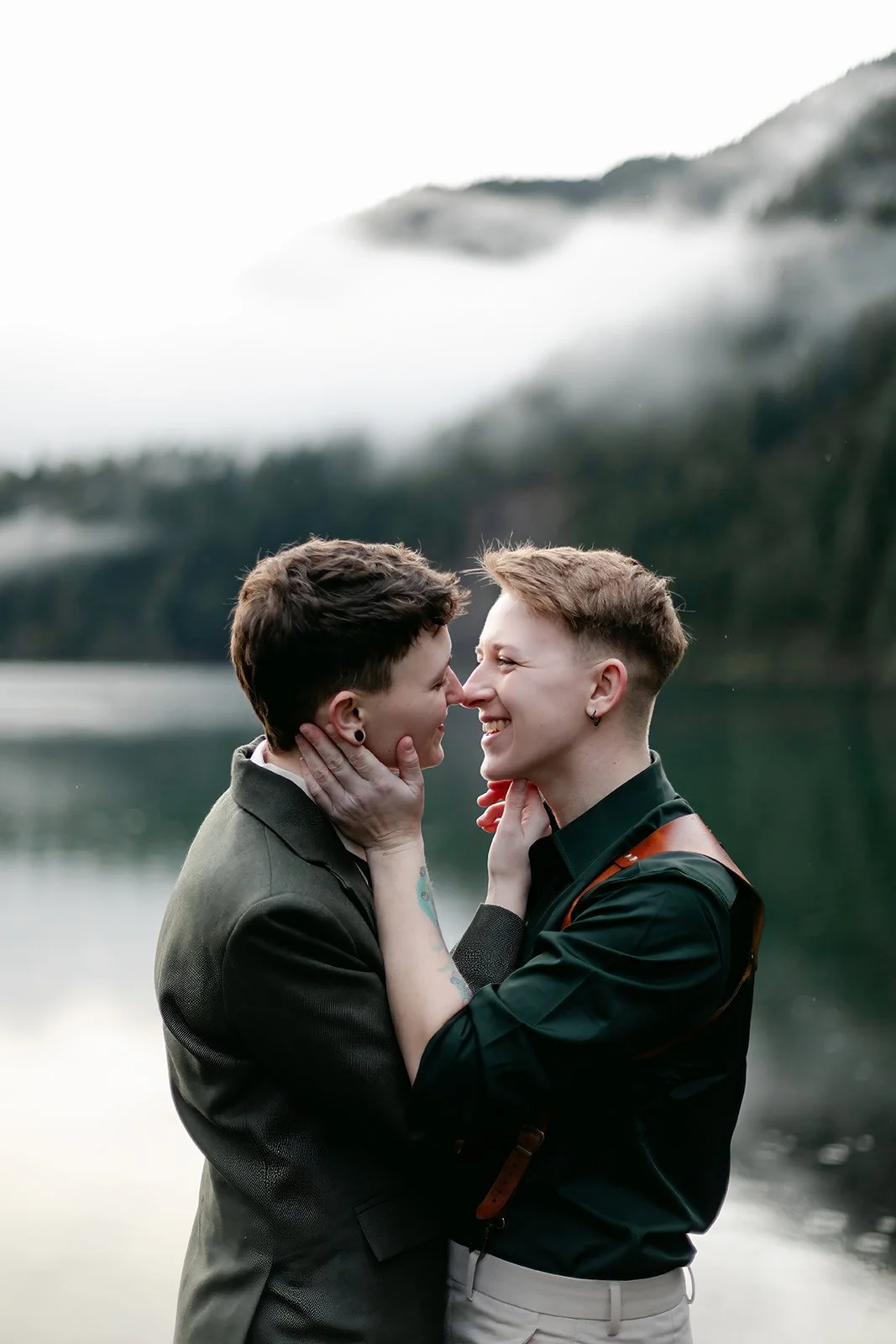 smiling lesbian couple on their wedding day at crescent lake in olympic national park, Washington state.