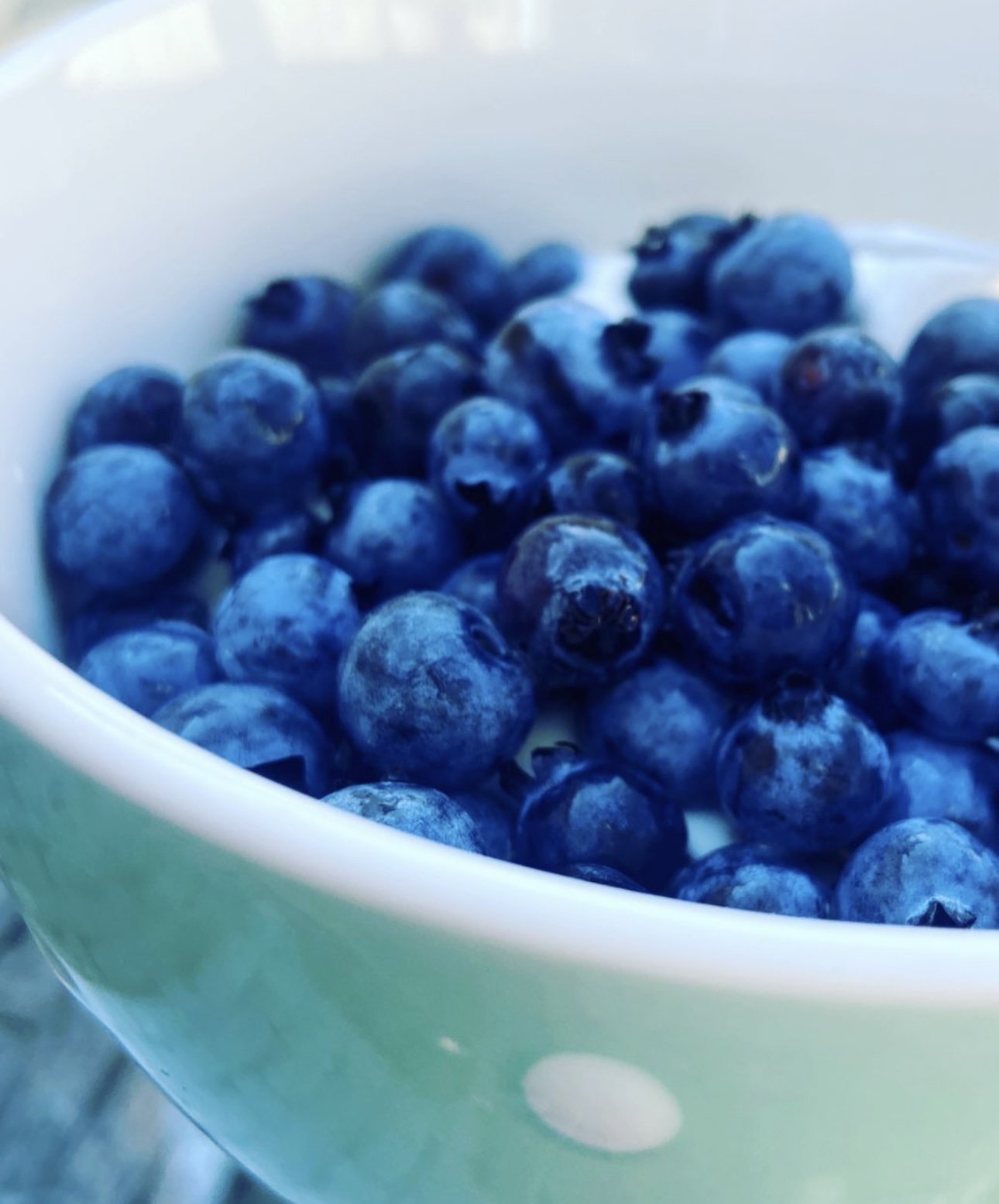 Close-up of fresh blueberries in a green bowl.