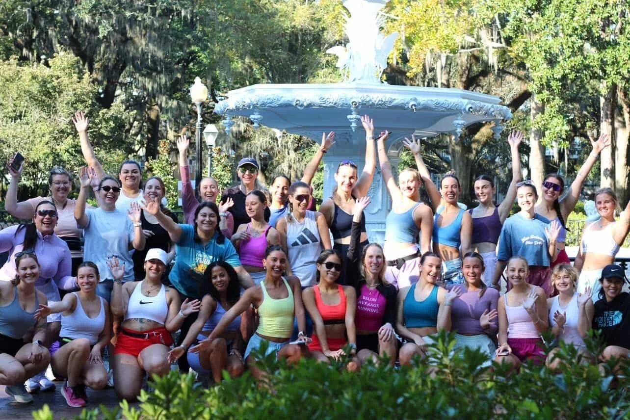 A group of women runners posing in front of the fountain in Forsyth Park.