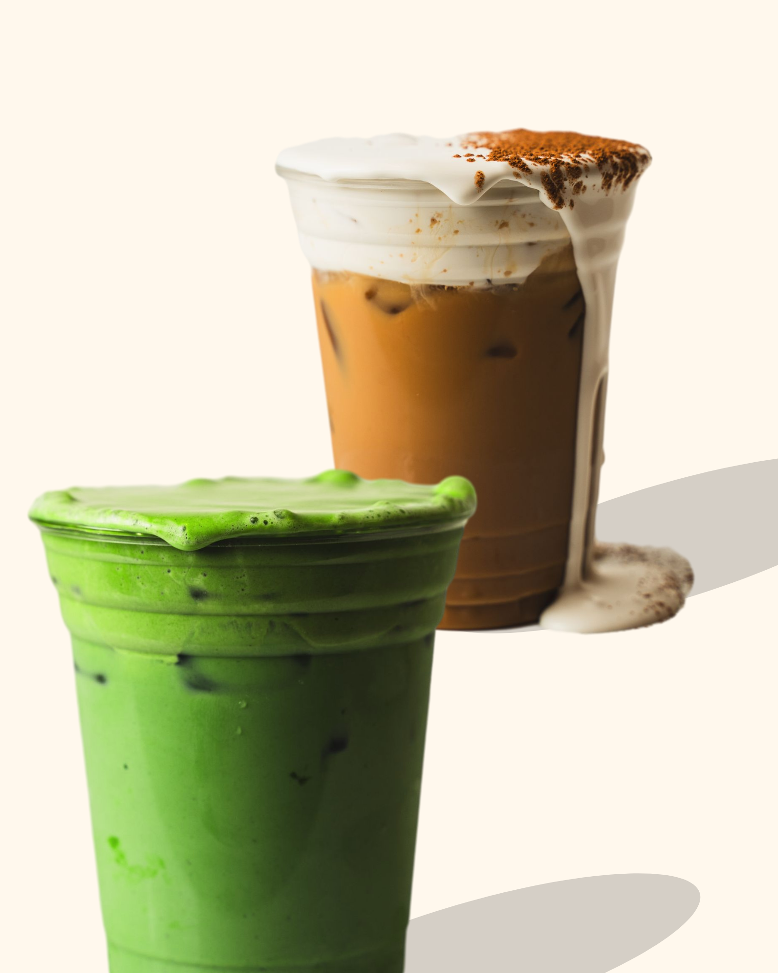 A green matcha latte in a tall glass with black specks, topped with foamed milk and chocolate or cinnamon powder. A partially visible iced coffee with foam and a brown coating is in a glass behind it.