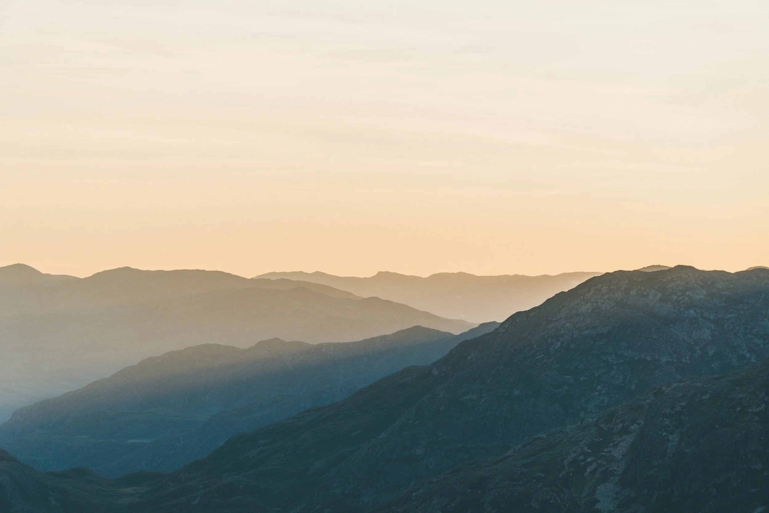 Photo of mountain ranges during sunset with soft, warm lighting and distant hills.