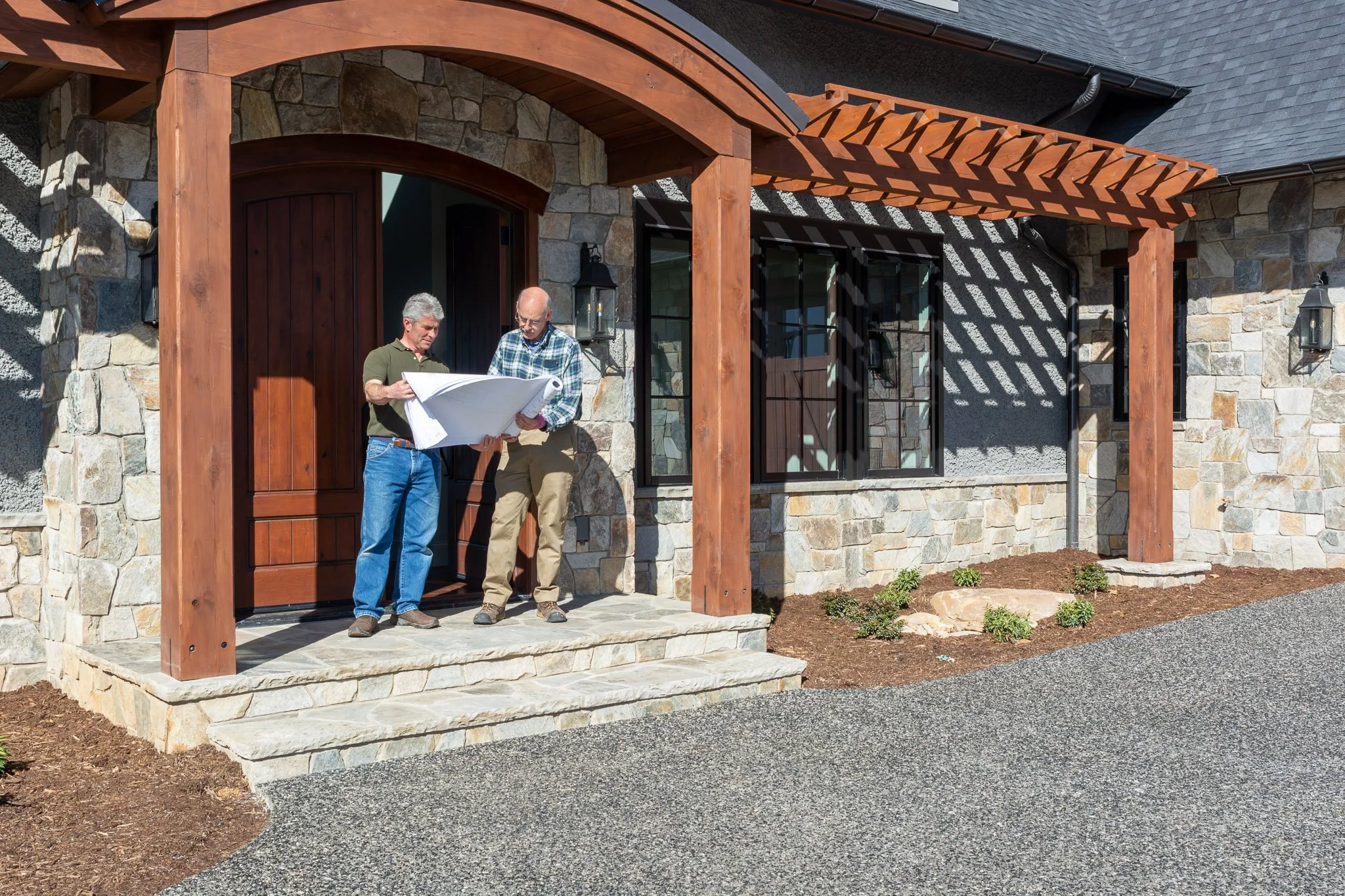 Custom builder Kevin Dolab reviewing project plans on a stone porch in
