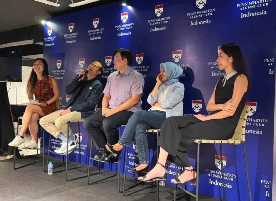 Five people seated on stage during a panel discussion at the Penn Wharton Alumni Club Indonesia event, with a blue backdrop featuring Penn Wharton logos.
