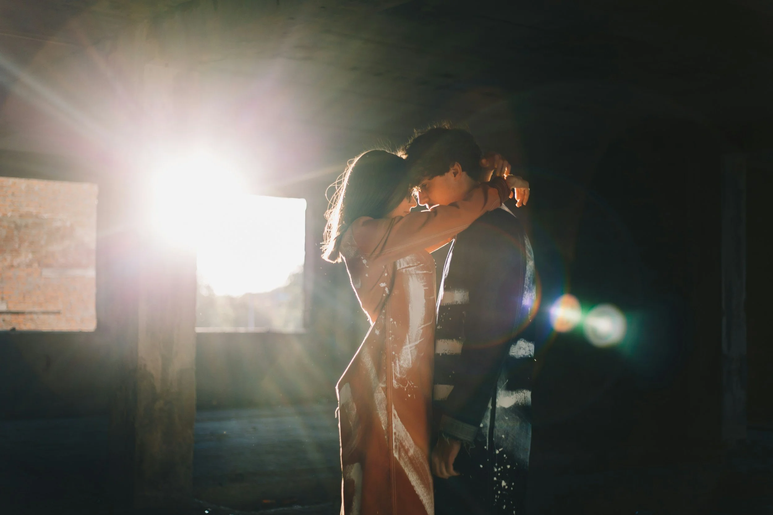 Couple sharing a close, intimate moment in sunlight, reflecting emotional and physical connection
