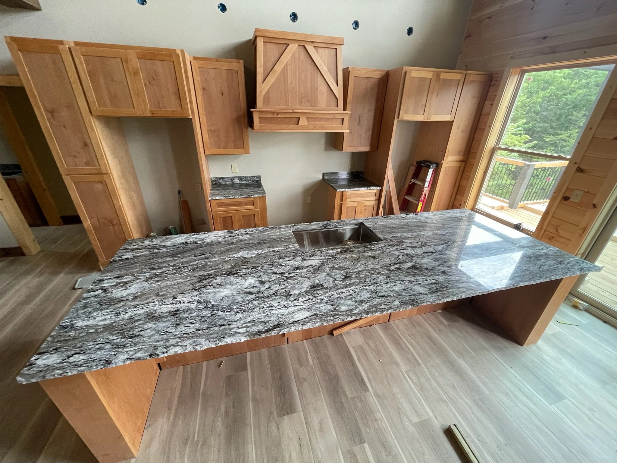 Kitchen with wooden cabinets and a large granite countertop island with a sink.