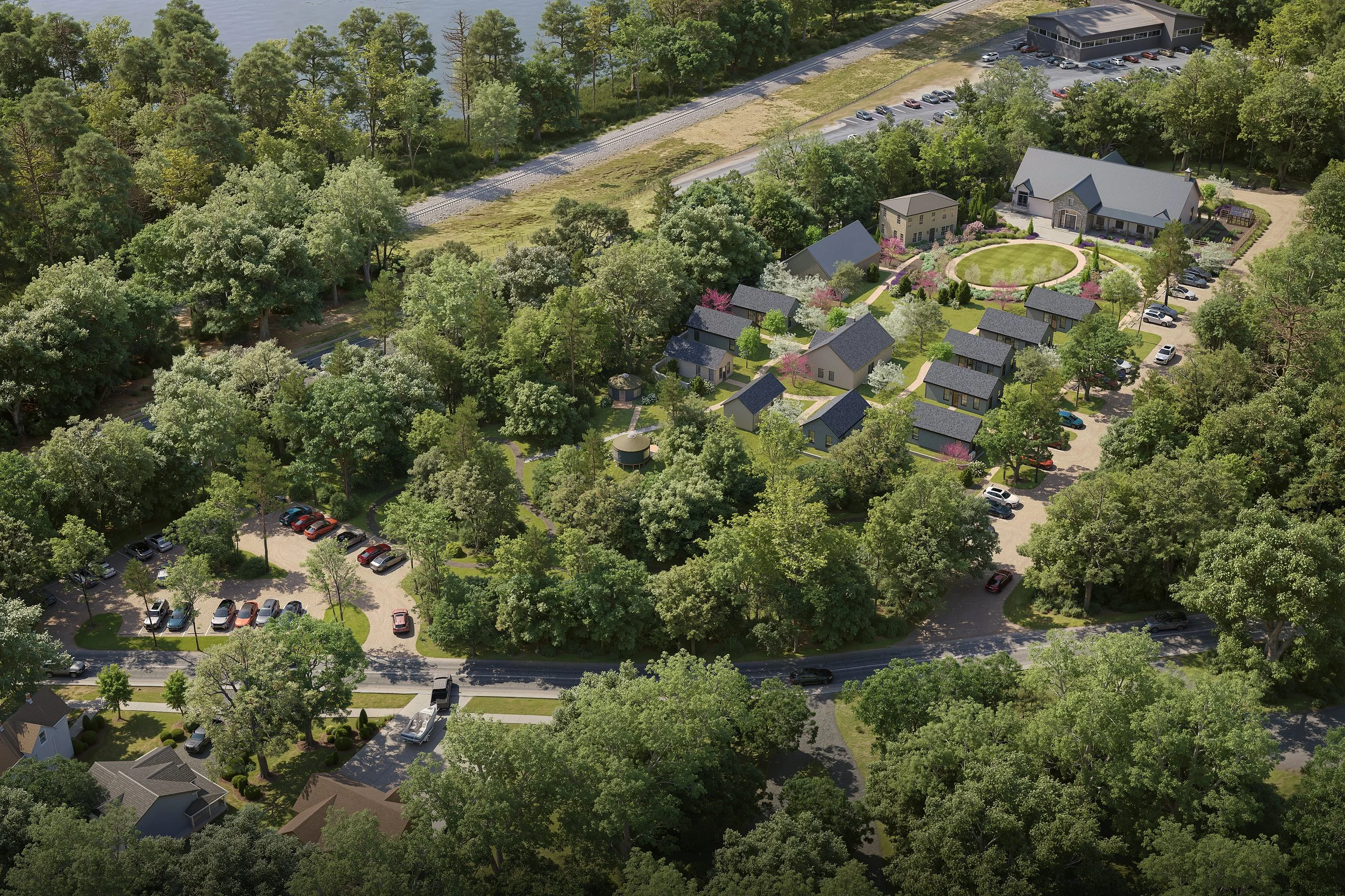 An aerial view of a residential neighborhood surrounded by lush green trees, with a large house and smaller houses, a parking lot, and a canal with trees along its bank.