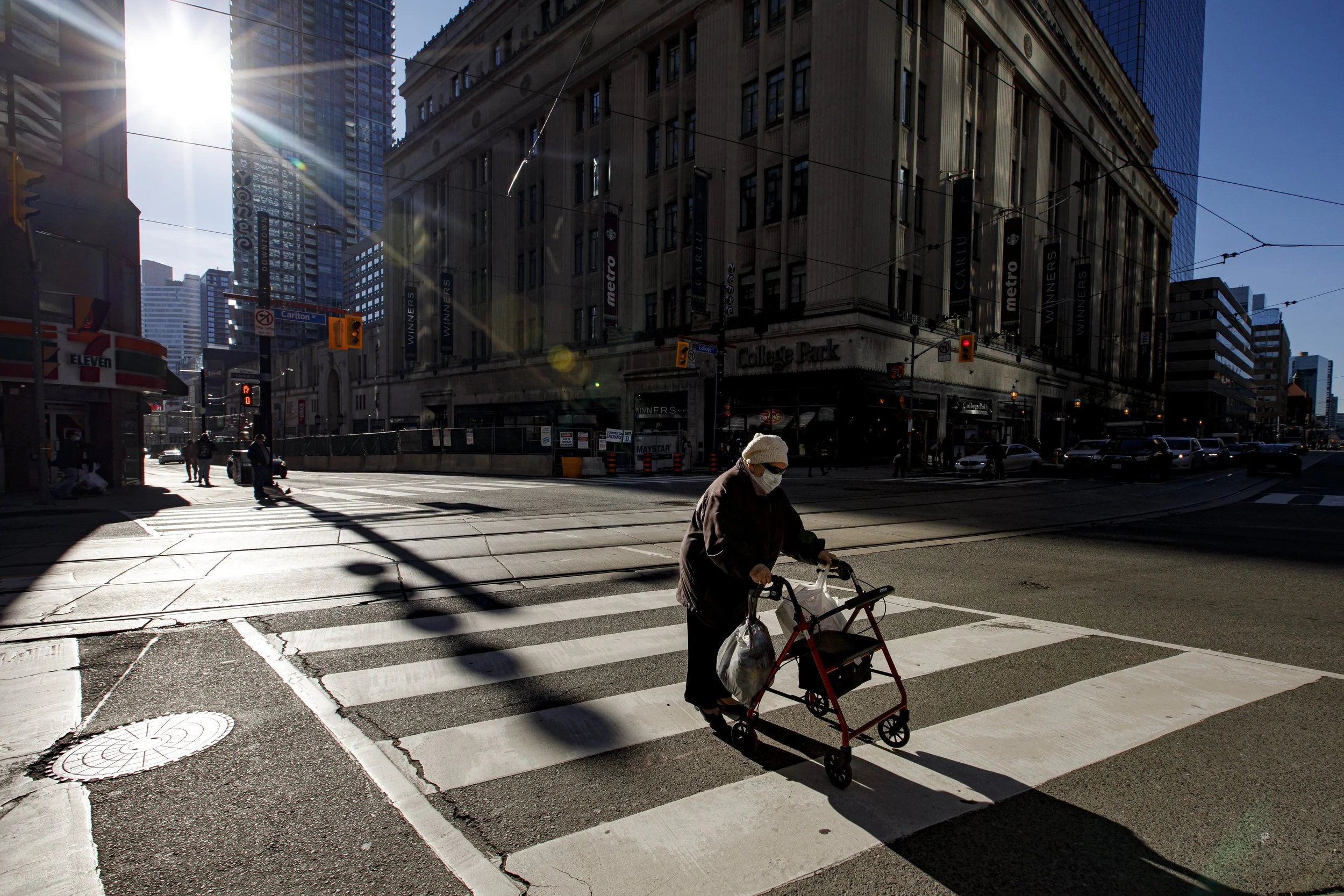 A senior, masked against the spread of the omicron variant of COVID-19, crosses the street in Toronto on Dec. 14, 2021.