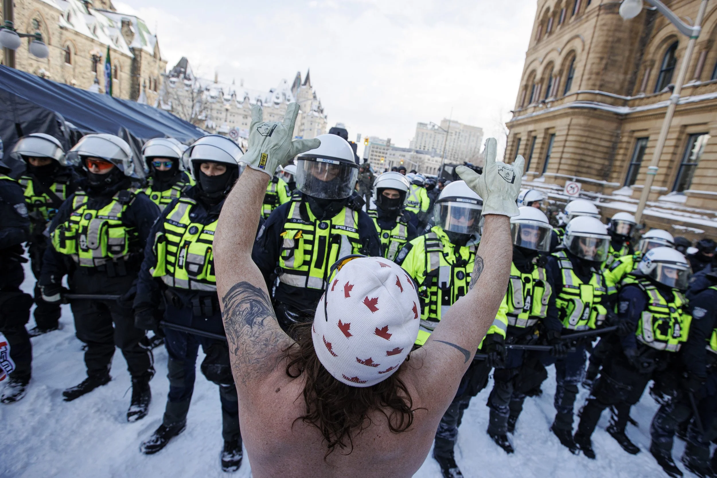 A shirtless demonstrator defies a line of police officers enforcing an injunction at an  encampment near Parliament Hill, in Ottawa, on Feb. 19, 2022.