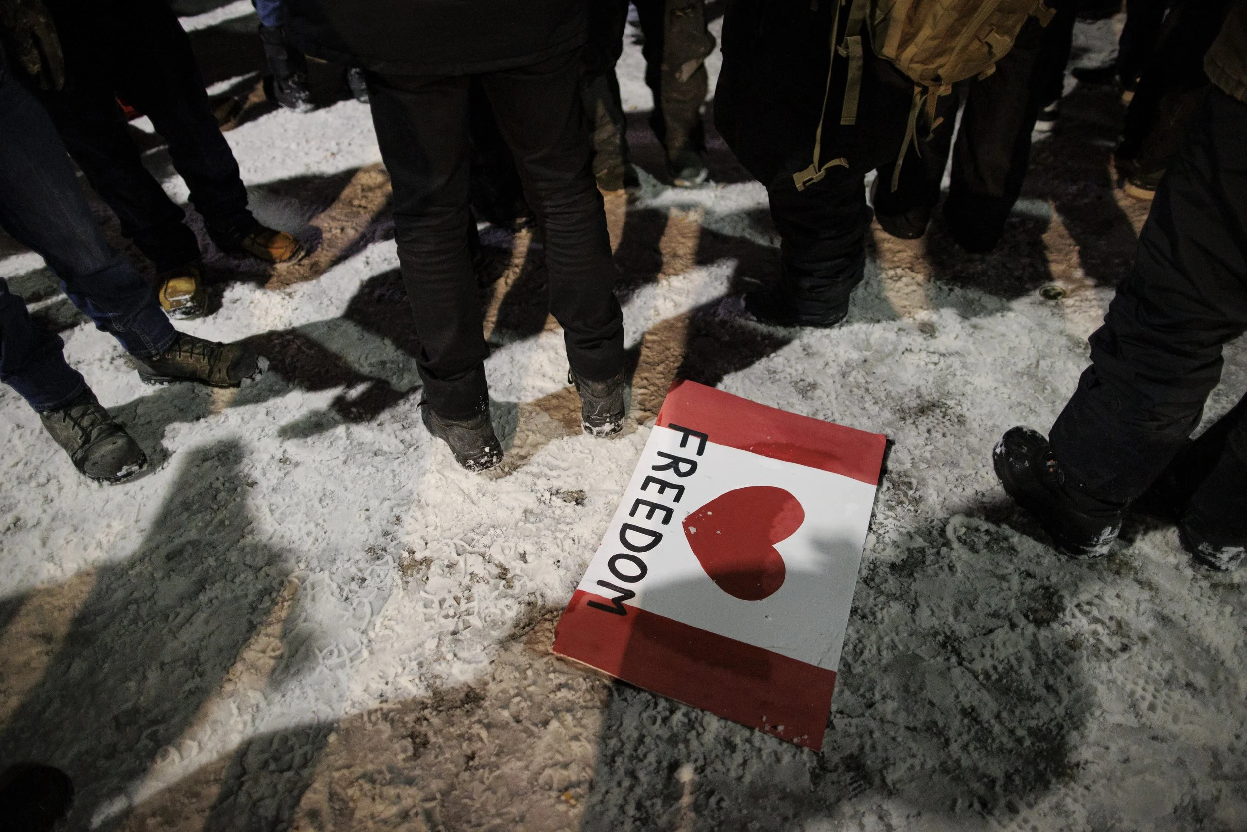 A 'freedom' placard is trampled in the snow as police from across the country enforce an injunction on Parliament Hill, in Ottawa, on Feb. 18, 2022.
