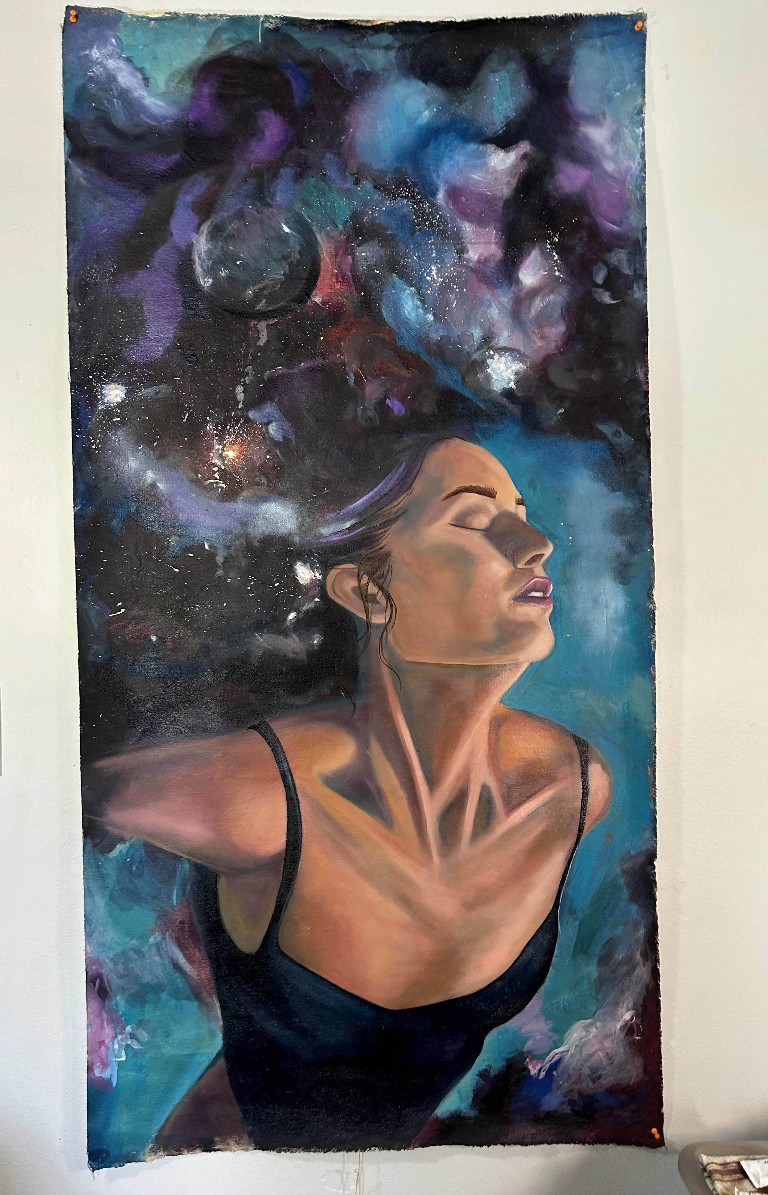 A painting of a woman with closed eyes and flowing hair blends into a cosmic scene with planets and nebulae.