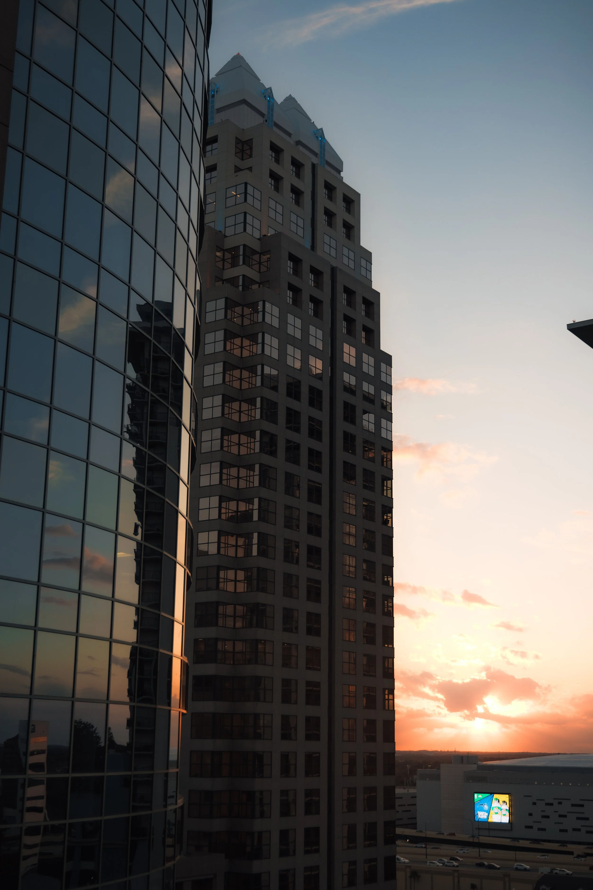 Tall buildings during sunset with reflections in glass windows.