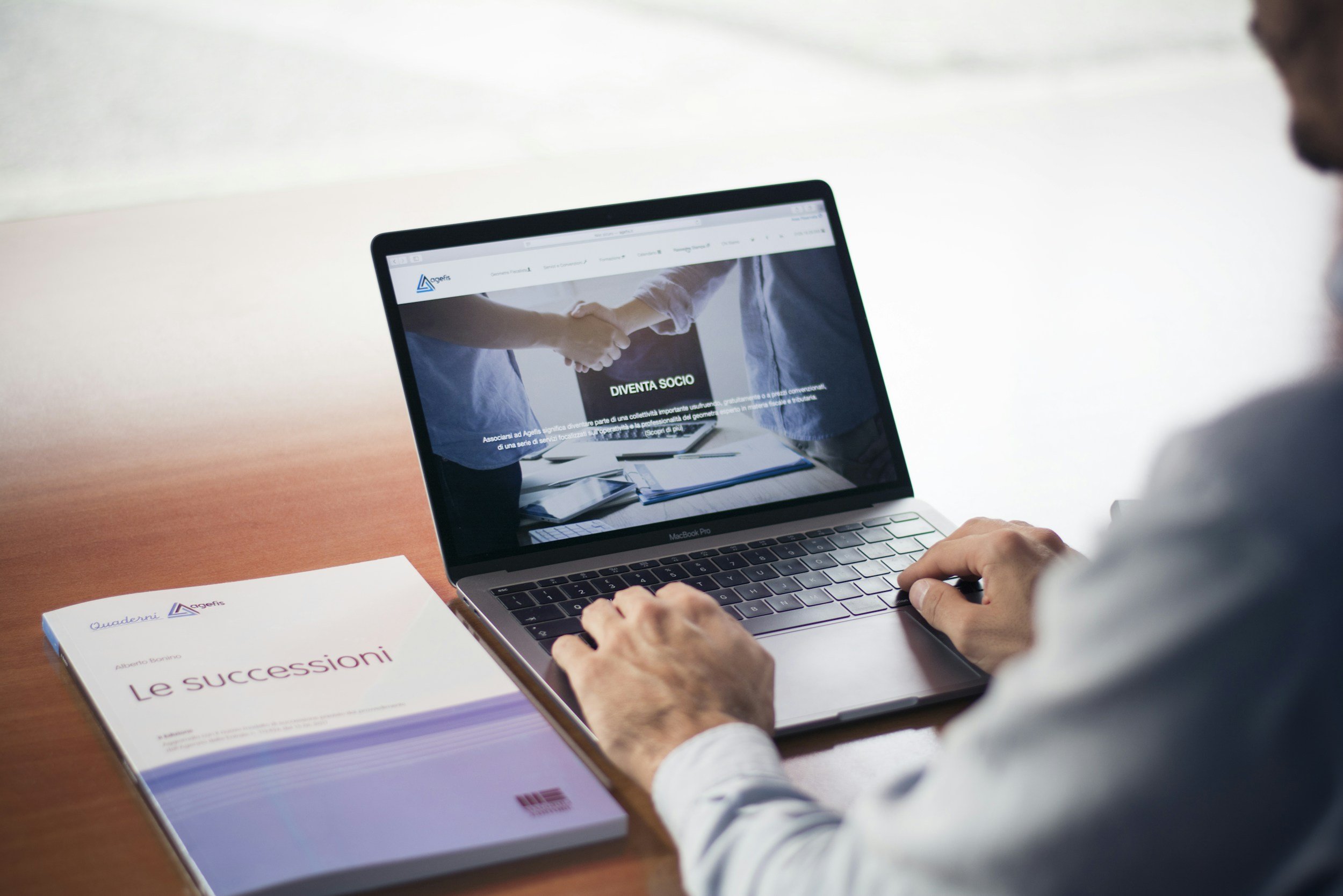 A person using a MacBook Pro laptop at a desk looking at a portal page.
