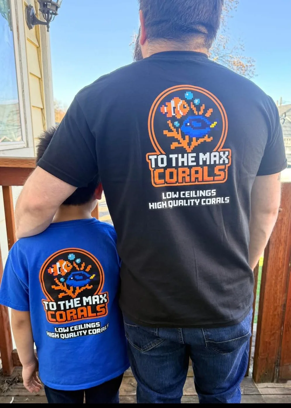 A father and son facing away from the camera showing their shirts, To The Max Corals company shirts.