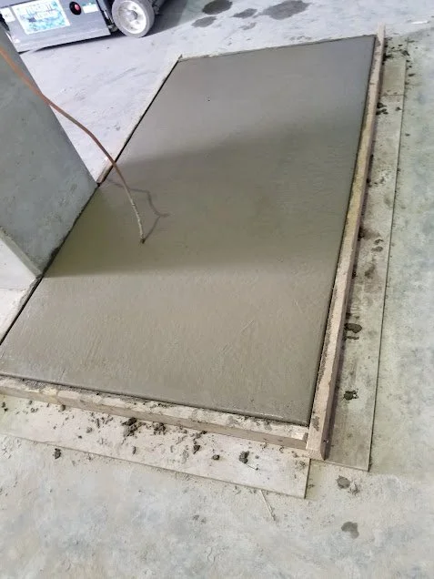 Concrete floor being freshly poured and leveled at a construction site.